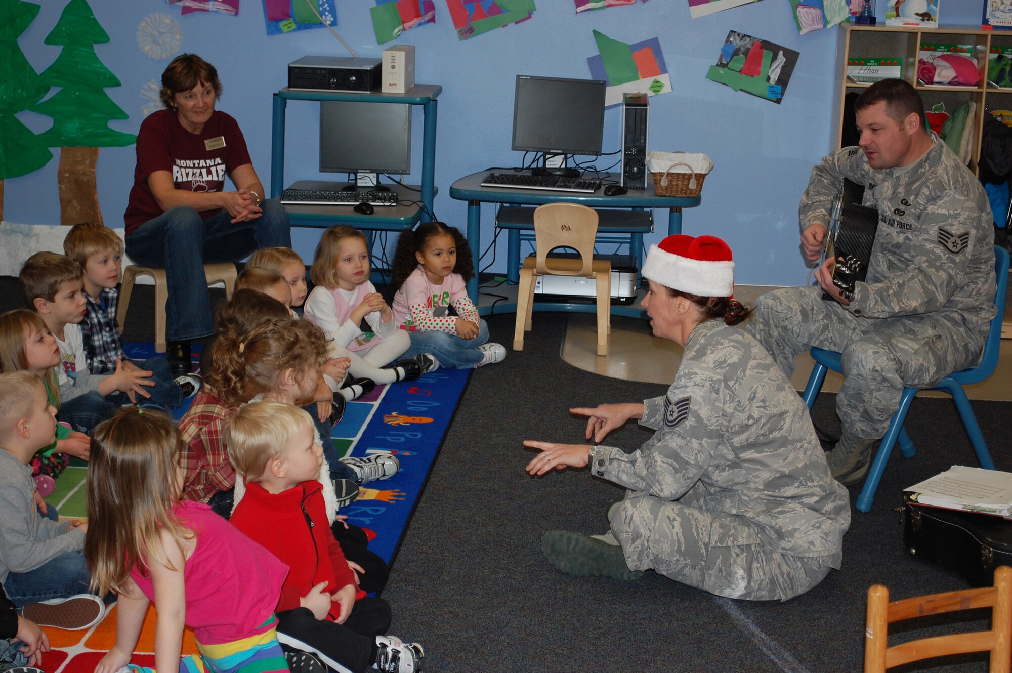 Tech. Sgt. Rebecca Packard and Staff Sgt. Daniel Bragdon, both U.S. Air Force Heartland of America Band members, sing Christmas carols to children at the Child Development Center. The duo made several stops around the base during their visit Dec. 15-16.