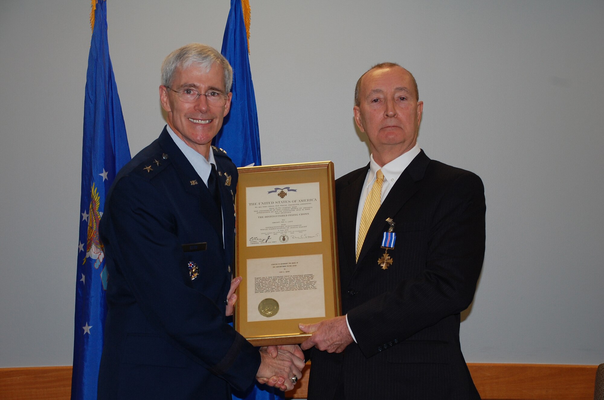 LACKLAND AIR FORCE BASE, Texas -- Maj. Gen. Robert Otto, commander of the Air Force Intelligence, Surveillance and Reconnaissance Agency poses for a photo with John LaHue, chief financial officer at the Air Force Center for Engineering and the Environment, upon presentation of a Distinguished Flying Cross to LaHue during his Dec. 22 retirement ceremony.  LaHue received the award in the mail in 1970 for his service in Vietnam, but was not formally presented the award until today.