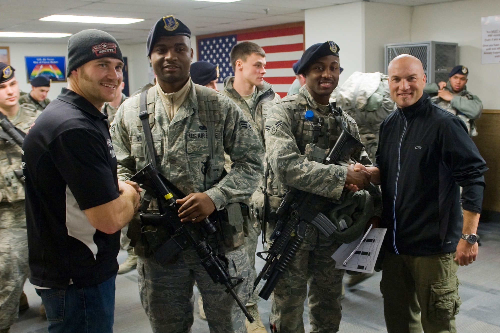 American300 Warrior Tour motivational speakers Mike Schultz (left) and Chad Crittenden (right) shake hands with 341st Security Forces Airmen about to go on duty following their evening guardmount Dec. 15. Senior Airman Antonio Simmons is inner left and Airman 1st Class Henry Robinson III is inner right. (U.S. Air Force photo/Beau Wade)
