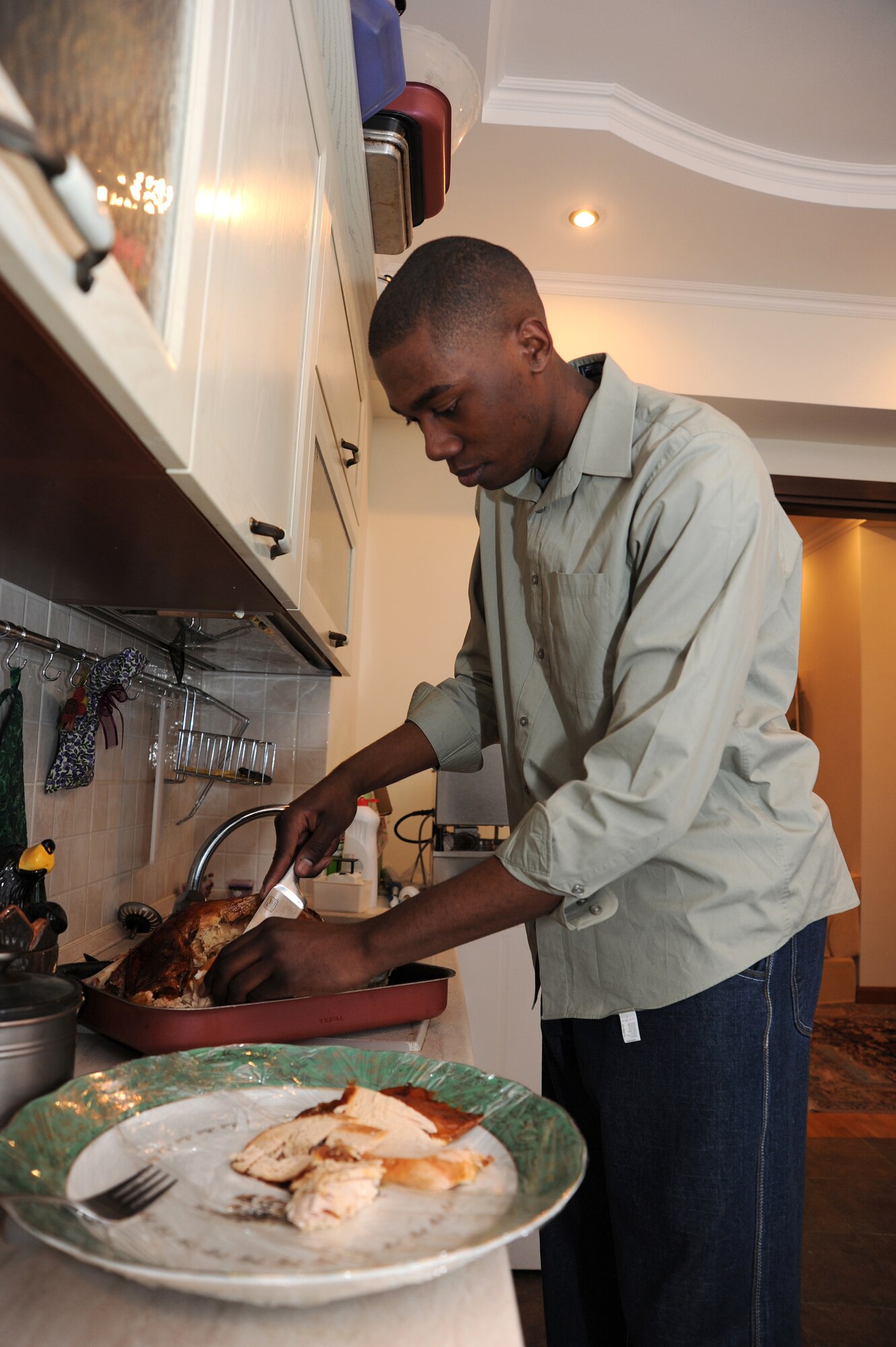 Airman 1st Class Saiquan Canty, 376th Expeditionary Logistics Readiness Squadron, carves a turkey at the home of Peggy and Travius Braun, U.S. Embassy partners in Kyrgyzstan, Dec. 24, 2011. Canty, deployed from Cannon Air Force Base, N.M., is one of seven service members from the Transit Center at Manas that was privileged to experience Christmas dinner with the Braun family who volunteered to host the service members.(U.S. Air Force photo/Staff Sgt. Angela Ruiz)