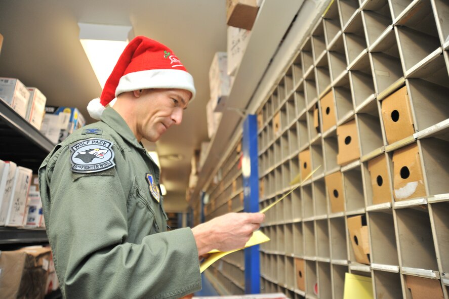 Col. Scott Pleus, 8th Fighter Wing commander, while volunteering his time at the Wolf Pack post office, places mail slips in boxes at Kunsan Air Base, Republic of Korea, Dec. 22, 2011. With a 40 percent increase in mail during the holiday season, Pleus volunteered to help separate and distribute mail to Airmen. (U.S. Air Force photo by Senior Airman Brittany Y. Auld/Released)