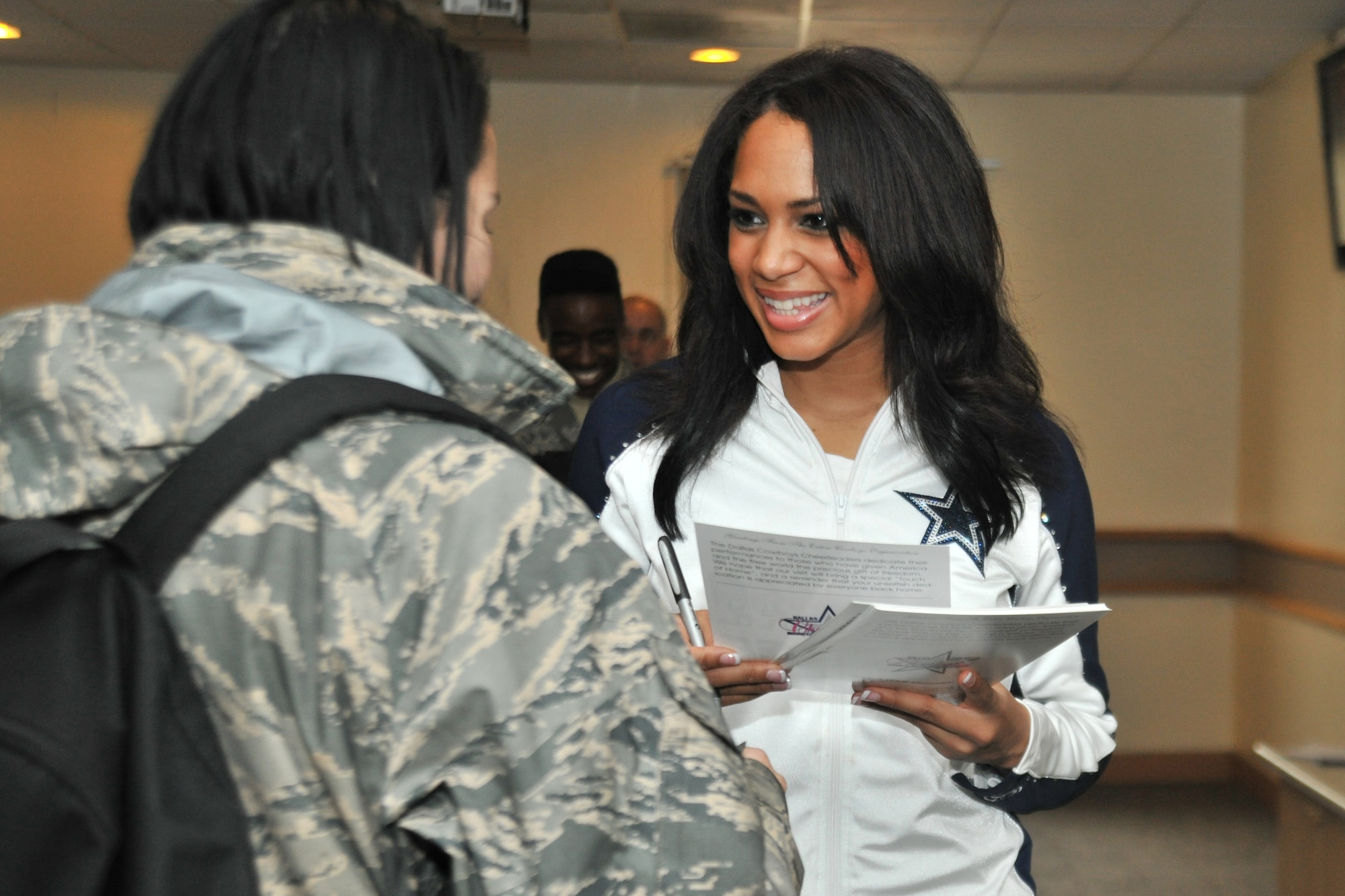 Mia Greenhouse, Dallas Cowboys cheerleader, autographs photos for Airmen at Kunsan Air Base, Republic of Korea, Dec. 21, 2011. The cheerleaders went to the O’Malley Dining Facility, Hangar 3 and the 8th Security Forces Squadron’s weapons simulation to autograph photos and take time to thank Airmen and Soldiers. (U.S. Air Force photo by Senior Airman Brittany Y. Auld/Released))