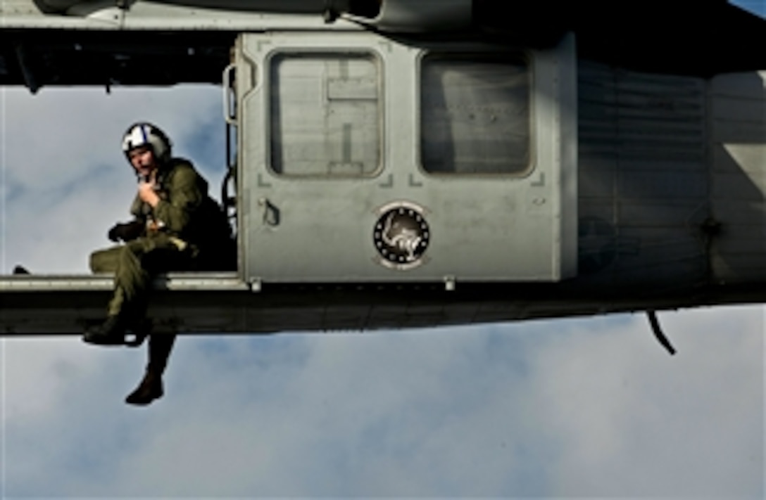 A U.S. sailor guides the pilots of an MH-60S K Night Hawk helicopter away from the landing area as they deliver supplies from the USNS Charles Drew to the USS Carl Vinson under way in the Pacific Ocean, Dec. 20, 2011. The sailor is assigned to Helicopter Sea Combat Squadron 12. The Carl Vinson and Carrier Air Wing 17 are on a western Pacific deployment. 