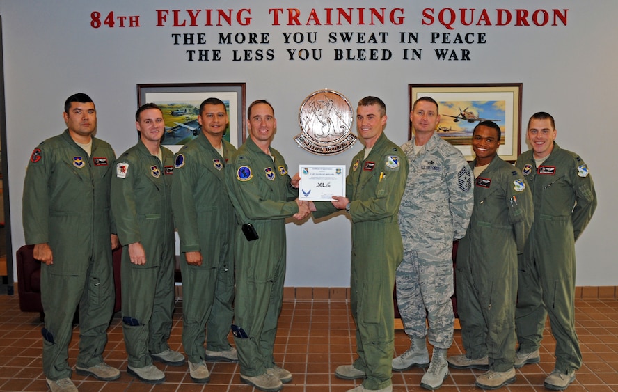 LAUGHLIN AIR FORCE BASE, Texas – Capt. Nathan Rogers accepts the XLer of the week award on behalf of the 84th Flying Training Squadron while posing with Col. Tom Murphy, 47th Flying Training Wing commander, and Chief Master Sgt. Ray Devite, 47th FTW command chief, here Dec. 14. The XLer is a weekly award chosen by wing leadership and given to those who consistently make outstanding contributions to Laughlin. (U.S. Air Force photo/Senior Airman Scott Saldukas)