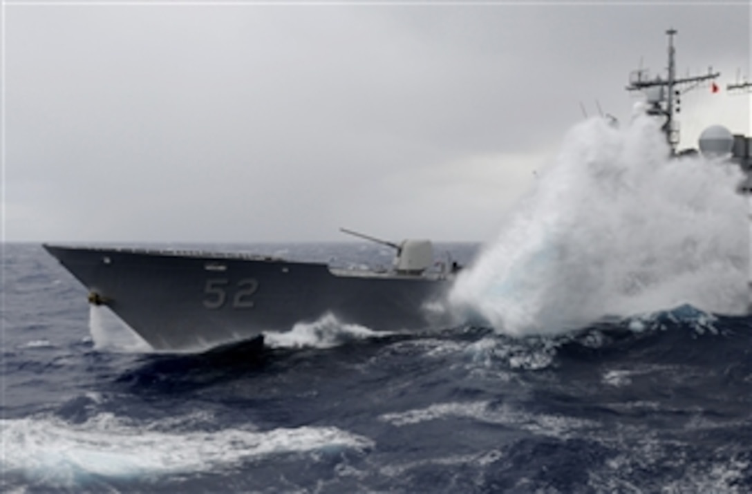 Waves break over the guided-missile cruiser USS Bunker Hill (CG 52) as the ship receives fuel from the aircraft carrier USS Carl Vinson (CVN 70) during a refueling at sea in the Pacific Ocean on Dec. 24, 2011.  The Carl Vinson and Carrier Air Wing 17 are underway on a western Pacific deployment.  
