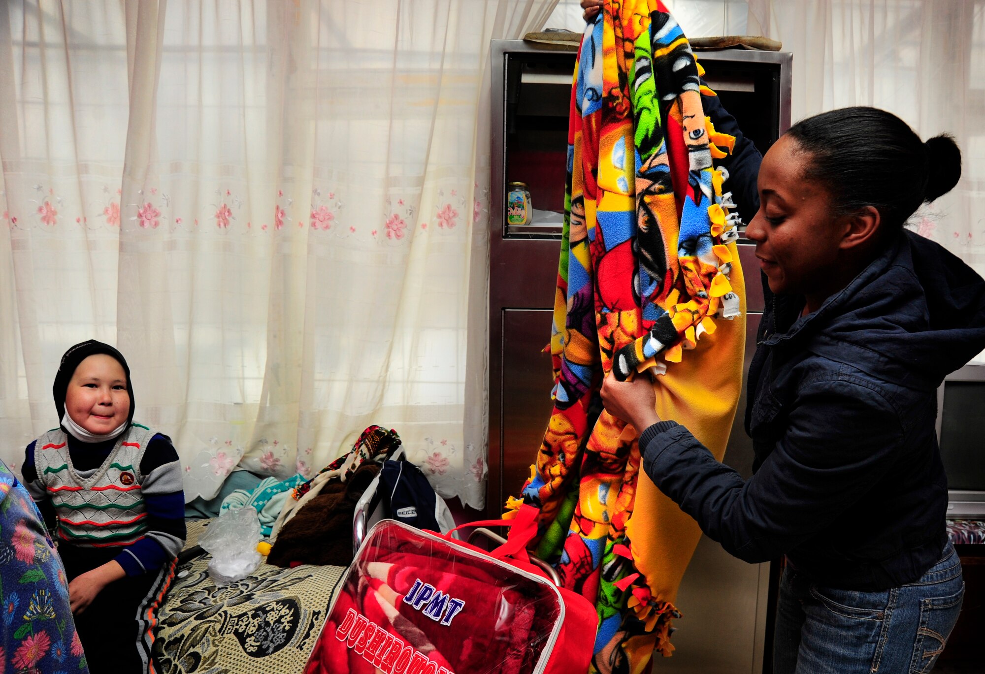 Staff Sgt. Kenyeta Brackett holds up a blanket for Islam Saidakmetov Dec. 28, 2011, at the Children's Cancer Center in Bishkek, Kyrgyzstan. The Manas Area Benefit Outreach Society distributed more than 40 winter coats and blankets to the center on behalf of the Transit Center in Manas, the Kyrgyz Republic and the U.S. Embassy as part of a partnership called "Operation Warm and Dry." The center treats children battling cancer from all over Kyrgyzstan and patients often stay at the cancer center up to two years for treatment. Brackett is a response force leader from the 376th Expeditionary Security Forces Squadron and is deployed here from Little Rock Air Force Base, Ark.(U.S. Air Force Photo/Staff Sgt. Angela Ruiz)