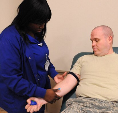LifeShare Donor Technician Kim Peoples prepares the arm of Tech. Sgt. Gregory Fuller, 2nd Communications Squadron quality assurance evaluator, for a blood donation at Hoban Hall on Barksdale Air Force Base, La., Dec. 28. LifeShare visits the base every month to collect valuable units of blood for use in local hospitals. (U.S. Air Force photo/2nd Lt. Tori Lalich)(RELEASED)