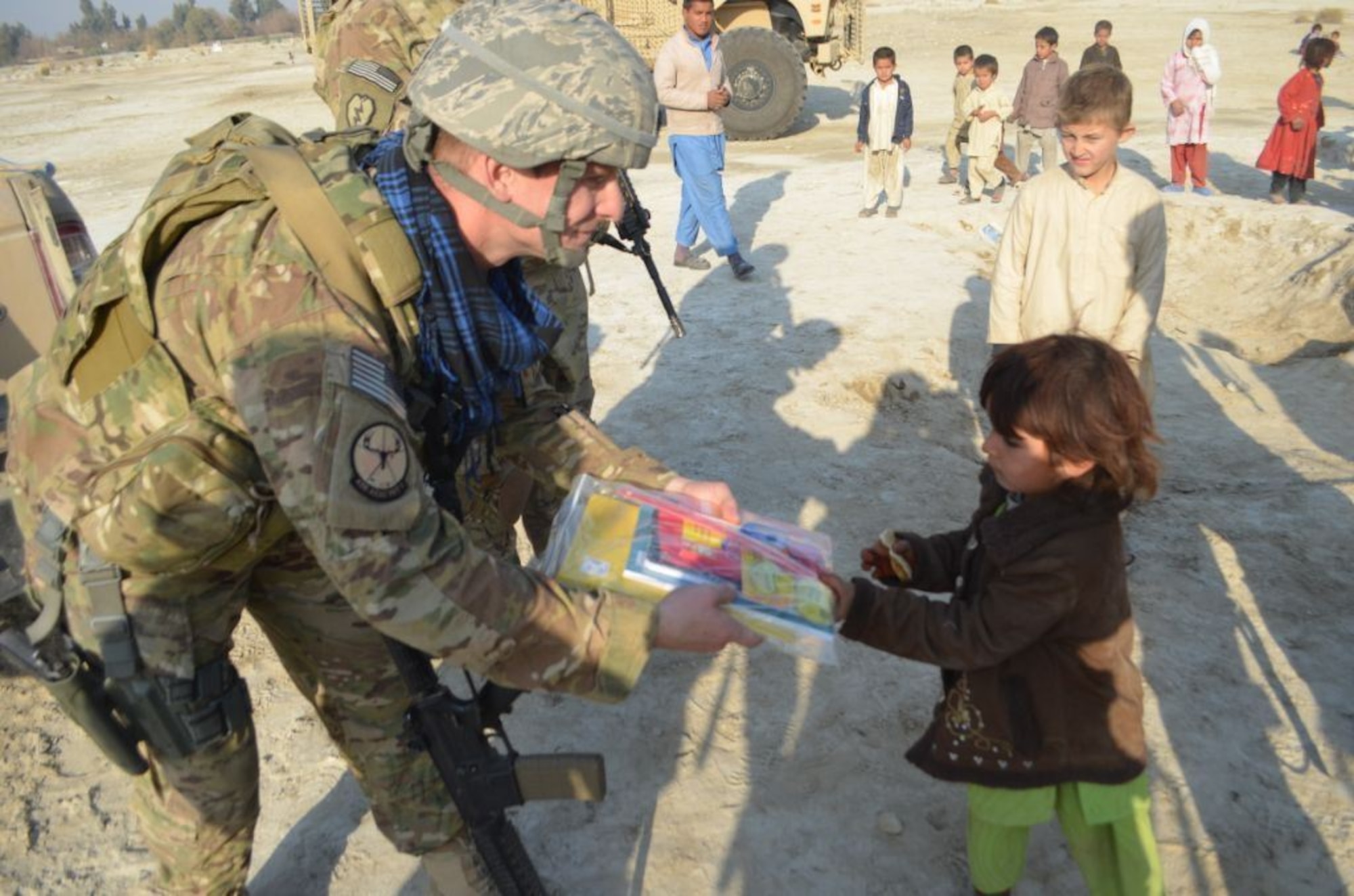 Lt. Col. Jason Wollard, Commander of Detachment 1, 438th Air Expeditionary Advisory Group, Kabul, Afghanistan, and members of his team hand out school supplies to Afghan children near Jalalabad, Afghanistan, Dec. 25. The 438th AEAG team was on a security mission with the U.S. Army and members of the Afghan Air Force when they stopped to distribute school supplies donated by families of U.S. Army personnel and members of the 438th AEAG to two tribal maliks, or chieftains, and the headmaster of a local school. Lt. Col. Wollard is deployed from the Safety  directorate at Air Force Global Strike Command, Barksdale Air Force Base, La. (U.S. Army photo by Specialist Erika Clarkson)
