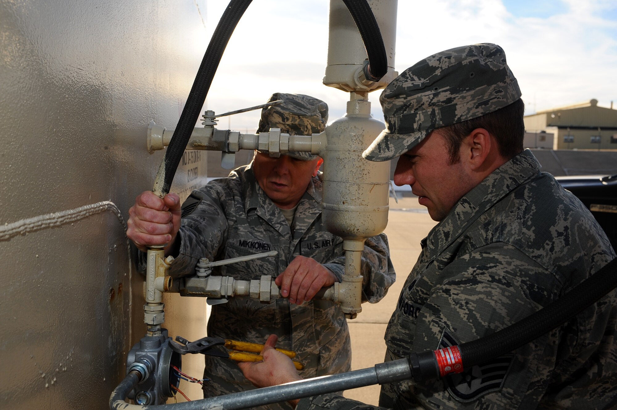 Staff Sgt. Erick Jensen, 28th Civil Engineer Squadron electronic systems technician, and Master Sgt. Rheiff Mikonen, 28th Logistics Readiness Squadron fields information service center section chief, replace an old and damaged low level fuel alarm system on a fuel tank on Ellsworth Air Force Base, S.D., Dec. 28, 2011. Fuel from the tanks is used to refuel the base’s B1-B fleet. (U.S. Air Force photo by Airman 1st Class Zachary Hada/Released)