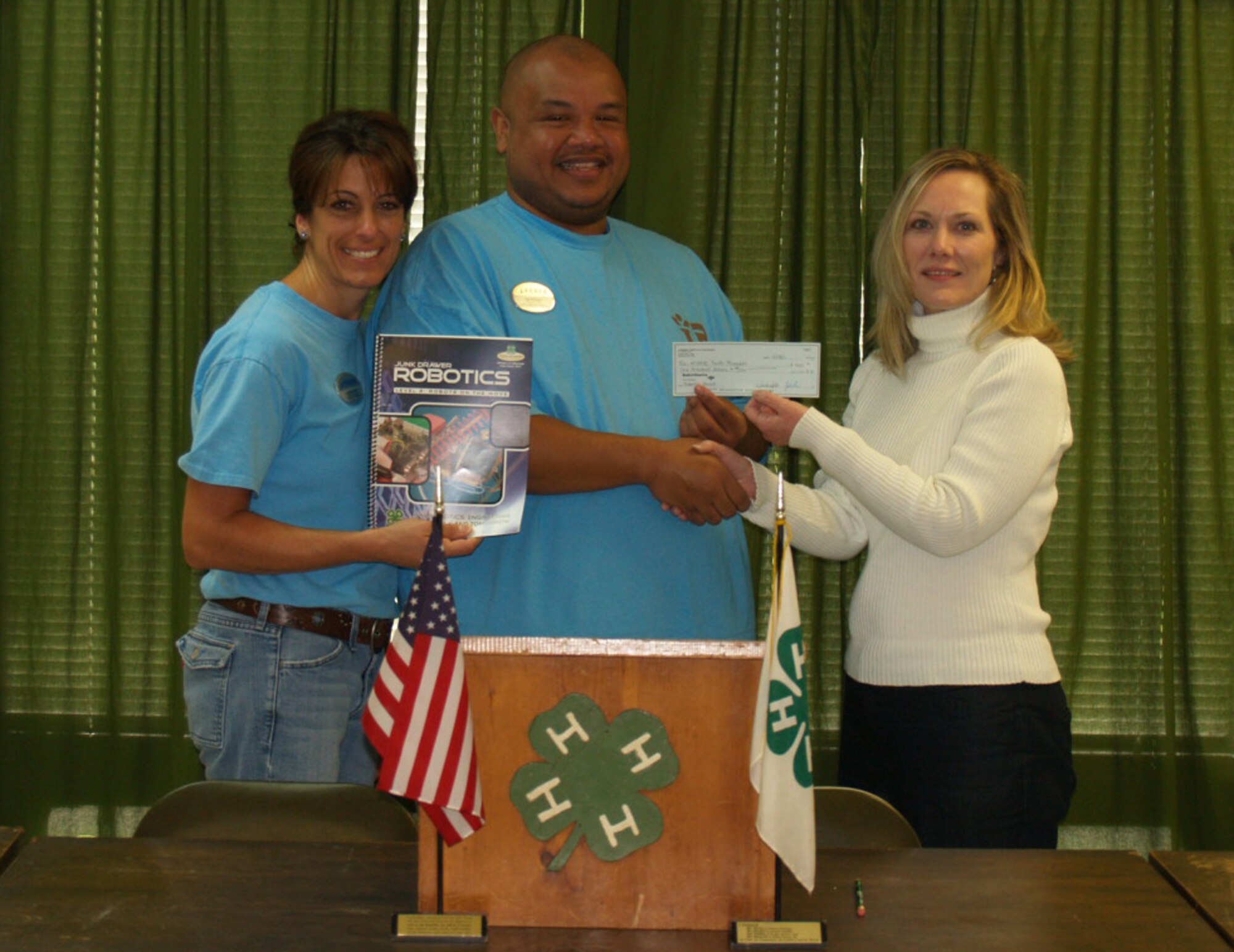 Debbie Allen, left, and Del Philpot, center, Moody Air Force Base School Age Program assistants, accept a $1,000 grant from Melinda Miller, 4-H agent Dec. 14, 2011, in Valdosta, Ga. The grant will be used to develop a Junk Drawer Robotics program aimed at helping fourth- to sixth-grade students developing science skills. (Contributed photos/Released)