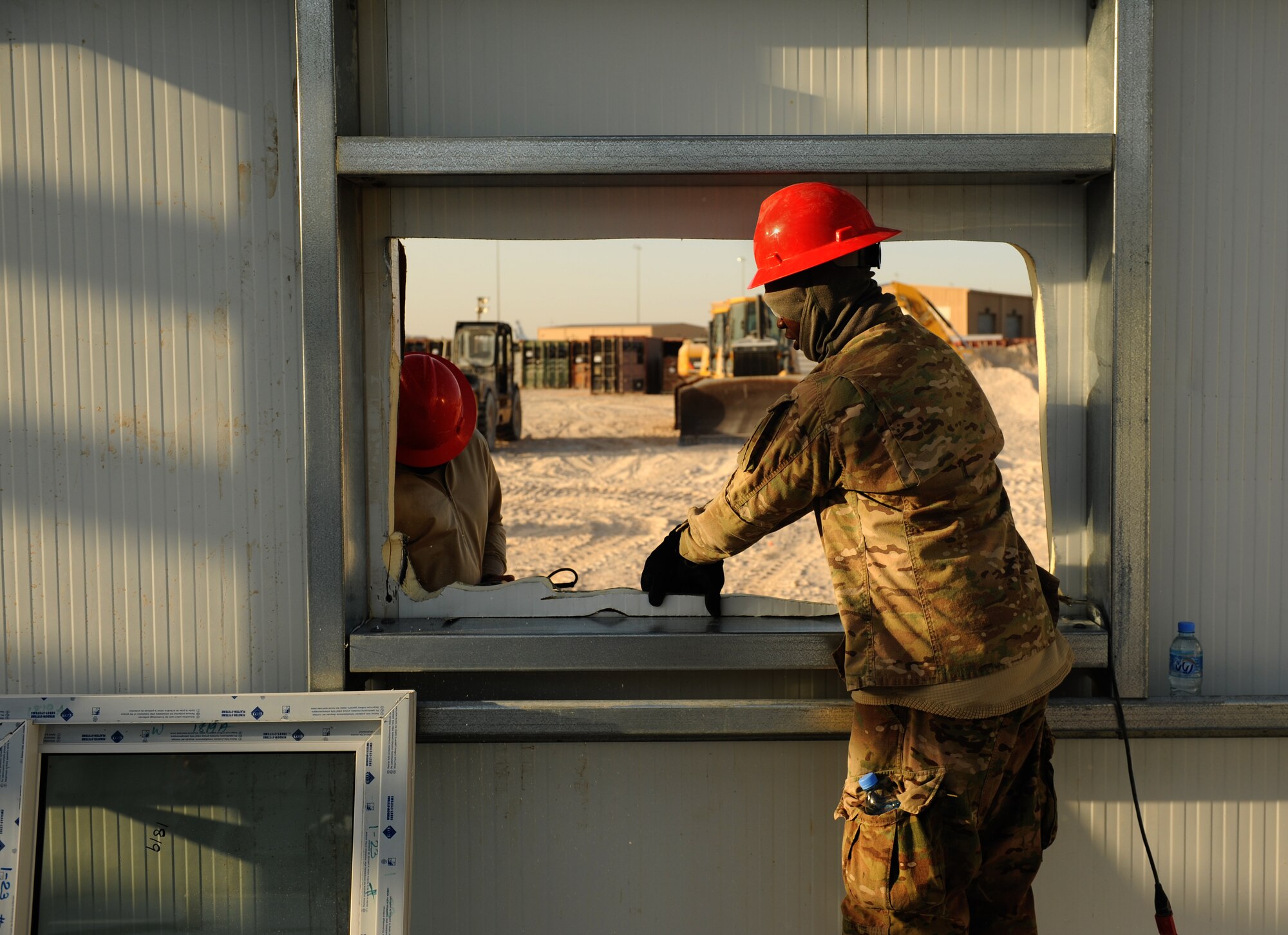 SOUTHWEST ASIA – Staff Sgt. McAnthony Teaste (right) holds trim as Airman 1st Class Clayton Crocker, saws excess trim off a window opening on a new RED HORSE facility here Dec. 28, 2011. Both Airmen are team members from the 557th Expeditionary RED HORSE Squadron.  The 9,000-square foot complex will house the 1st Expeditionary RED HORSE Group Headquarters.  Teaste, a native of Myrtle Beach, S.C., is deployed from Seymour Johnson Air Force Base, N.C. Crocker, a native of Davie, Fla., is deployed from Nellis Air Force Base, Nev. RED HORSE stands for Rapid Engineer Deployable, Heavy Operations Repair Squadrons, Engineer. (U.S. Air Force photo/Staff Sgt. Nathanael Callon) 