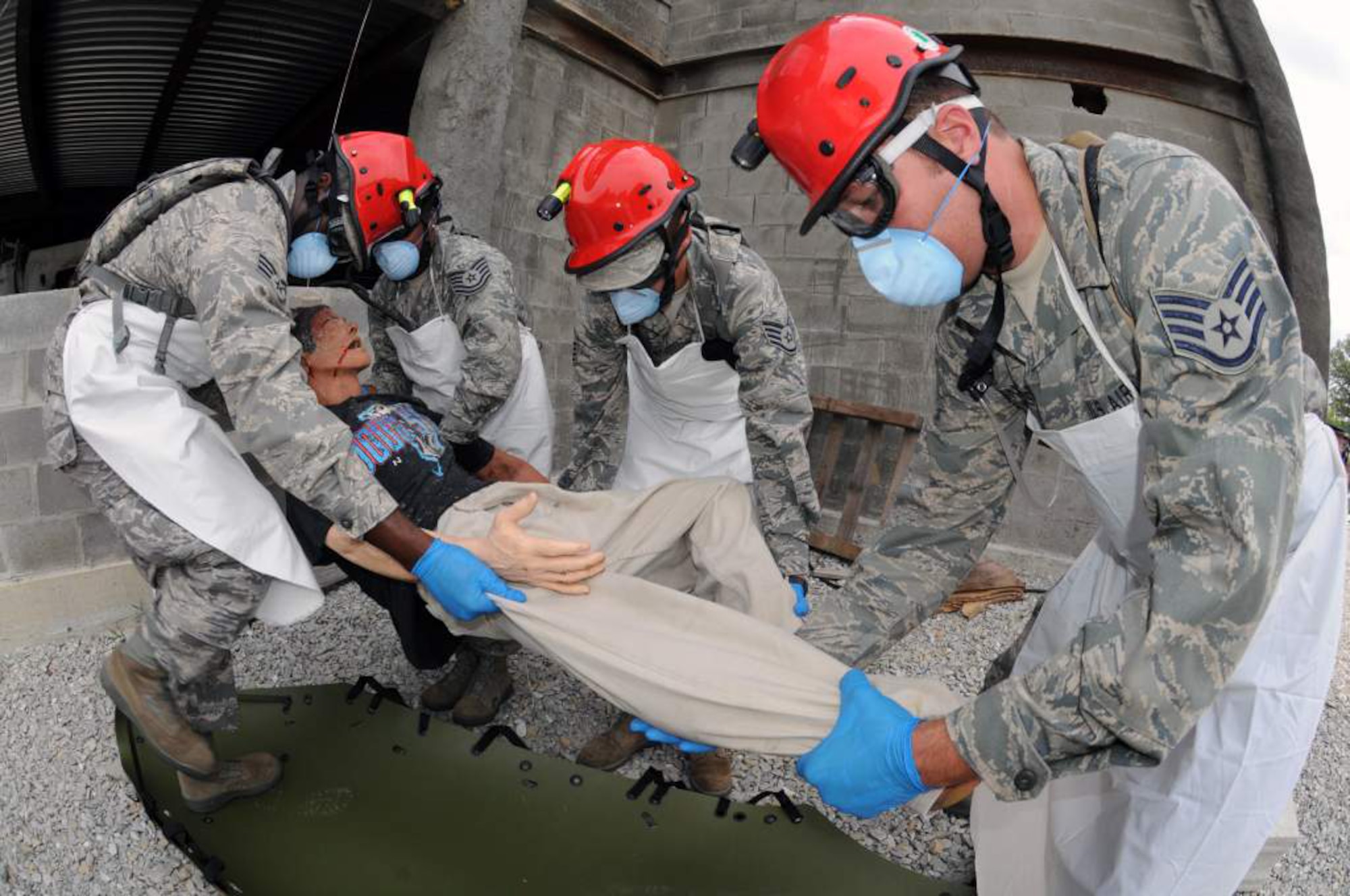Air National Guard Fatality Search and Recovery Team members collect a simulated casualty from a collapsed parking garage at Muscatatuck Urban Training Complex near Camp Atterbury, Ind., on Aug. 18, 2011, as part of Vibrant Response 12. From left to right are Senior Airman Kevin Woodard and Tech. Sgt. Brittany Ingram of the Kentucky Air Guard; Staff Sgt. Jeffrey Feliciano of the Puerto Rico Air Guard; and Staff Sgt. Jason Gallegos of the Colorado Air Guard. (U.S. Army photo by Staff Sgt. Keith Anderson)