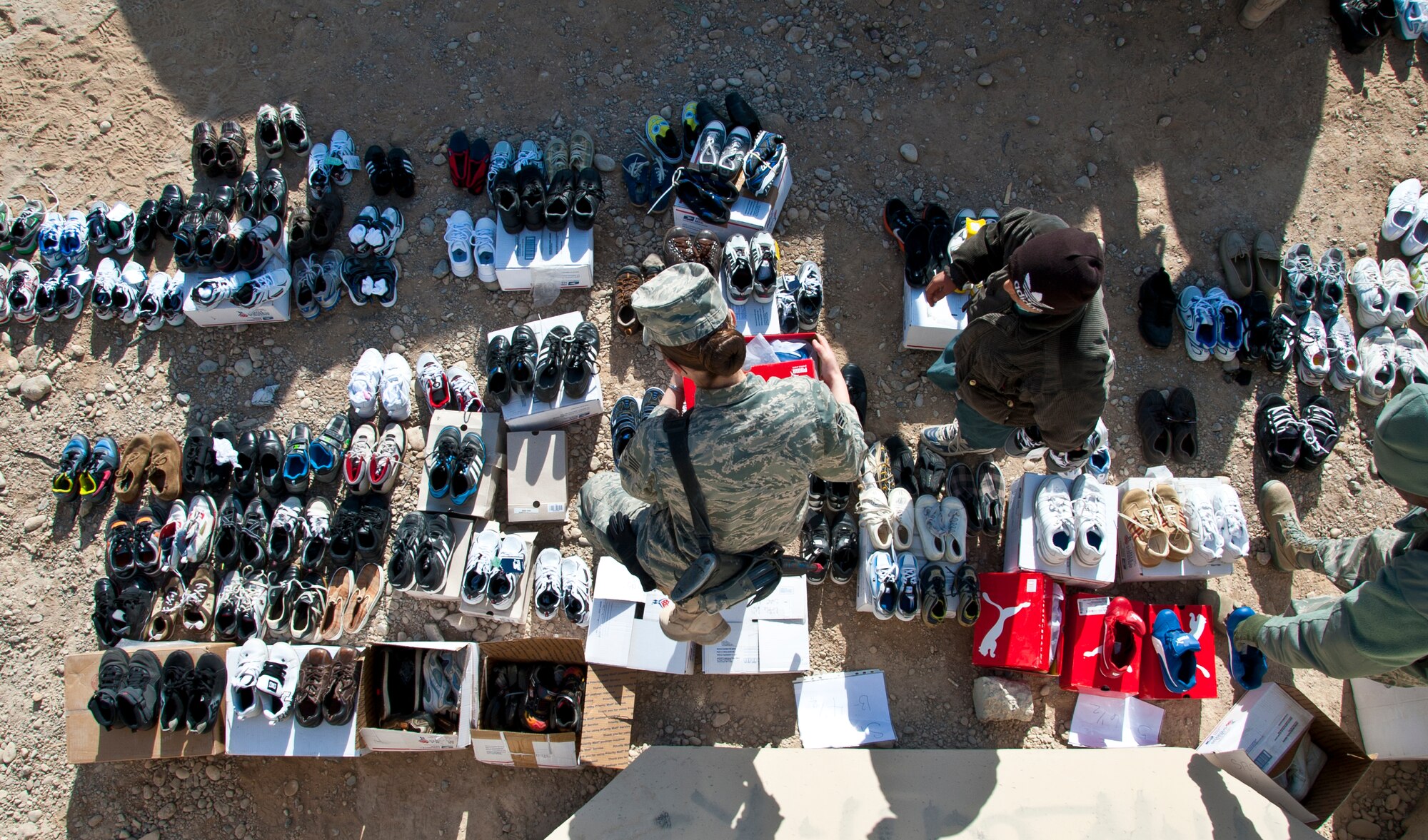 KANDAHAR AIRFIELD, Afghanistan -- A volunteer helps a young local Afghan boy find the correct size shoe at the Bazaar School at Kandahar Airfield, Afghanistan, Dec. 31, 2011. Volunteers throughout Kandahar collected more than 600 shoes to provide to children. The volunteers also fitted the children in the correct shoe sizes to educate them on the importance of proper shoe fitting. (U.S. Air Force photo by Staff Sgt. David Carbajal)