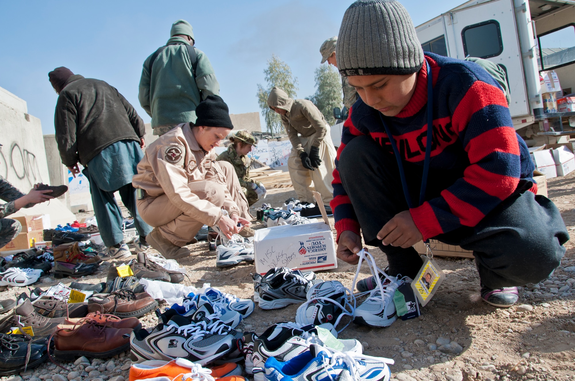 KANDAHAR AIRFIELD, Afghanistan -- A young local Afghan boy unties a pair of new shoes to try them on at the Bazaar School at Kandahar Airfield, Afghanistan, Dec. 31, 2011. Volunteers throughout Kandahar collected more than 600 shoes to provide to children. The volunteers also fitted the children in the correct shoe sizes to educate them on the importance of proper shoe fitting. (U.S. Air Force photo by Staff Sgt. David Carbajal)