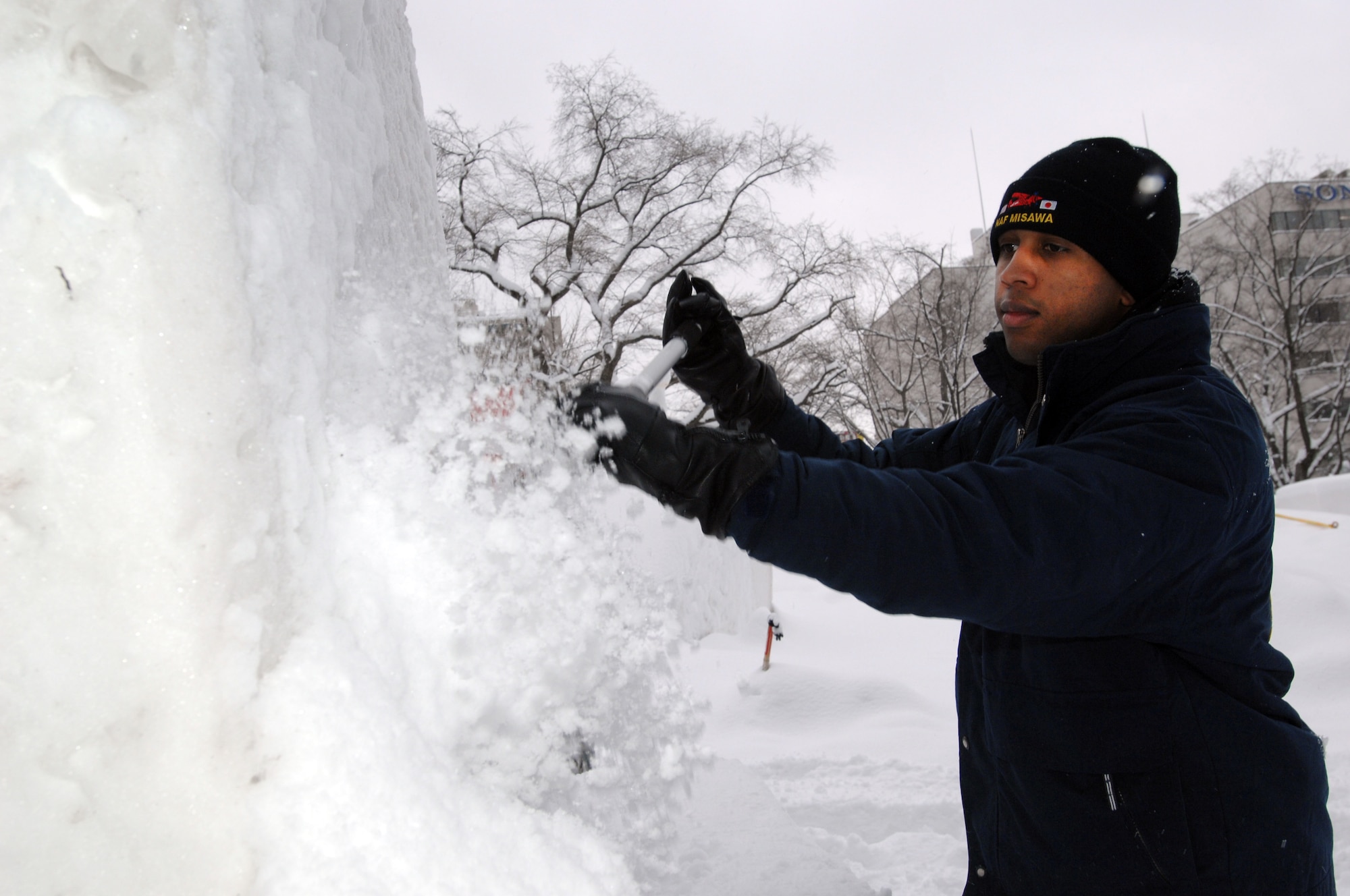 U.S. Navy Operations Specialist 3rd Class Draylon Polk, Misawa Navy Snow Team member, removes residual snow from a nine-foot compacted block of snow Feb. 1, 2011, Sapporo, Japan. Polk and his team members will spend the week sculpting the snow into an "ice anchor," which is slated for display at the 62nd Annual Sapporo Snow Festival. Polk is stationed on board Misawa Air Base and is attached to Commander Task Force 72. (U.S. Navy photo by Chief Mass Communication Specialist Daniel Sanford/Released)