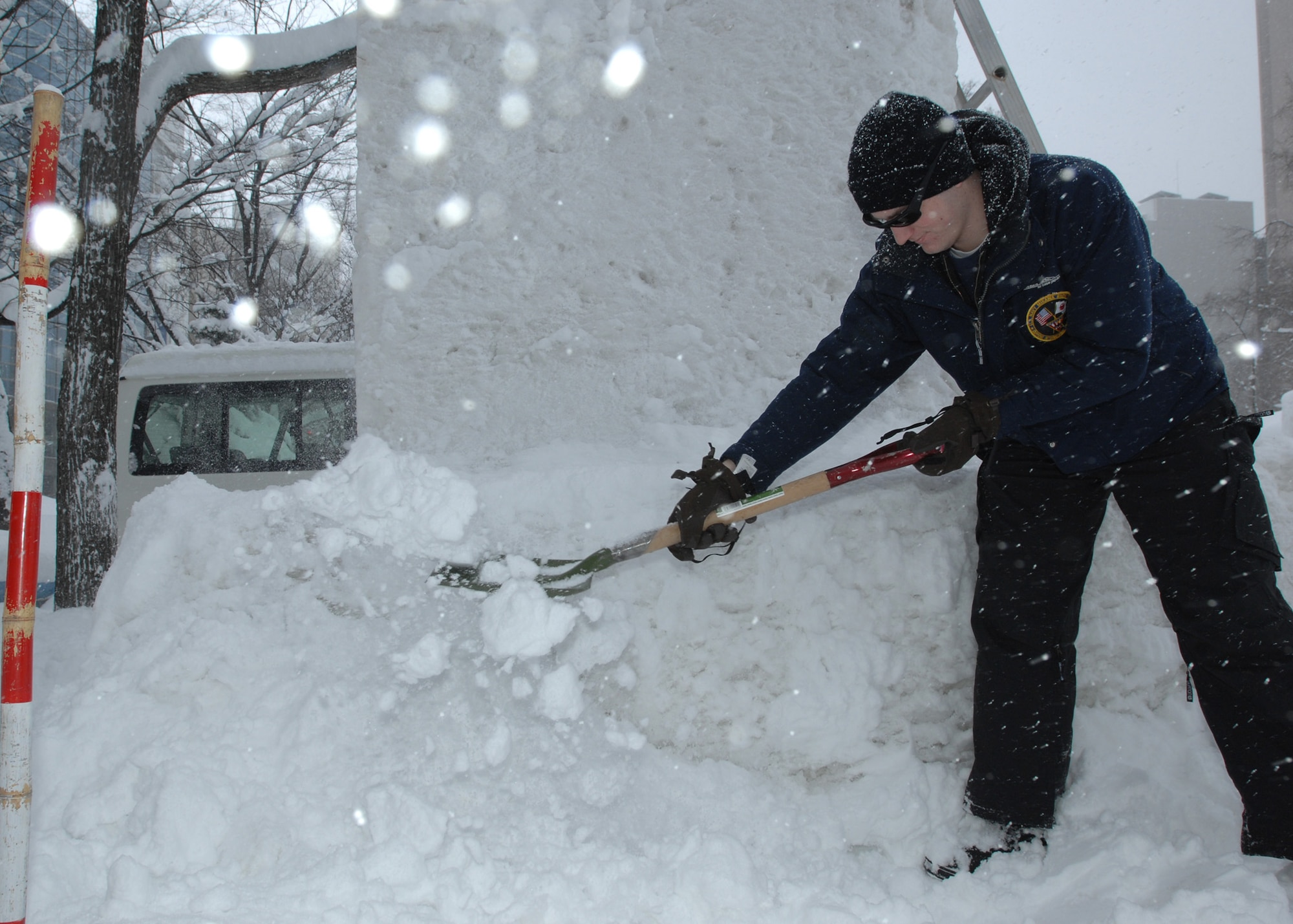 U.S. Navy Informations Systems Technician 3rd Class Daniel Grimes, Misawa Navy Snow Team member, clears snow away from a nine-foot tall block of compacted snow Feb. 1, 2011, Sapporo, Japan. Grimes and his team members are in Sapporo for the city's annual snow festival and are creating an anchor-shaped snow sculpture for display at the event. More than five feet of snow fell upon Sapporo overnight, which meant the team had to clear the way to their entry just to get started. Grimes is stationed at Misawa Air Base and is attached to Navy Information Operations Command, Misawa. (U.S. Navy photo by Chief Mass Communication Specialist Daniel Sanford/Released)