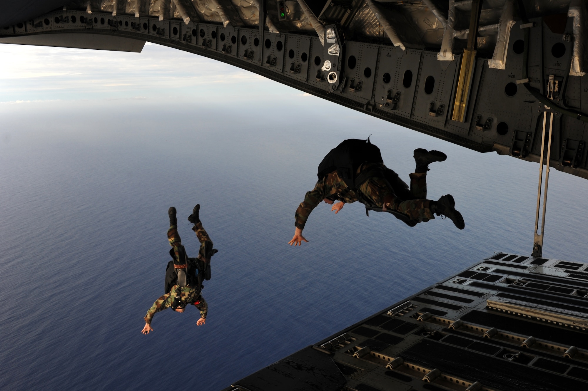 Navy Special Warfare Unit ONE jumpers bail out of the back of a C-17 Globemaster III after the aerial drop of a Maritime Craft Aerial Delivery System drop Jan. 13. Airmen from Joint Base Pearl Harbor-Hickam, Hawaii, worked with the Naval unit to deploy the boat off the coast of Guam while merging the capabilities of the U.S. Air Force and the U.S. Navy. (U.S. Air Force photo/Staff Sgt. Mike Meares)