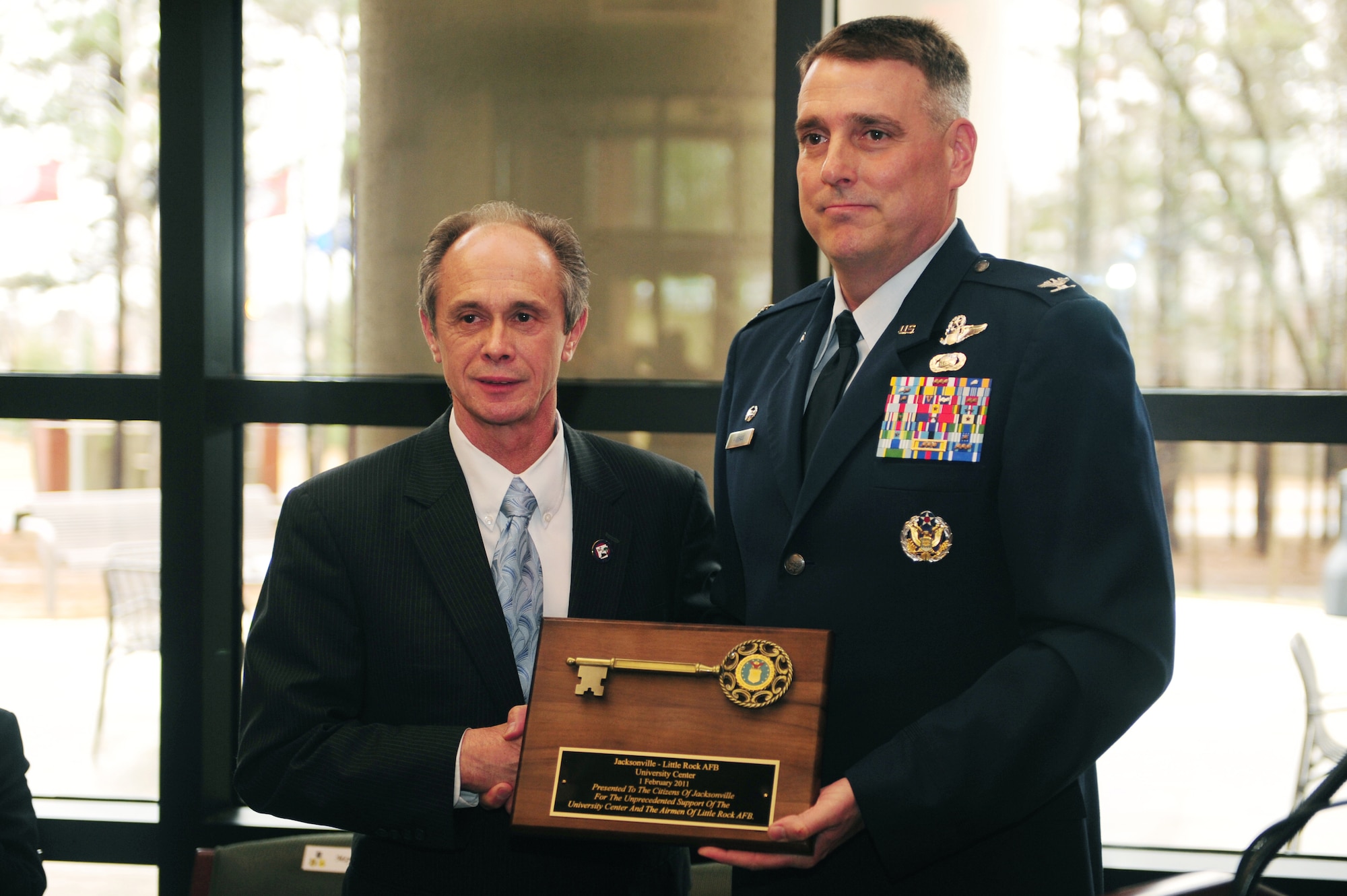 Col. Mike Minihan (right), 19th Airlift Wing commander, hands a key to Jacksonville Mayor Gary Fletcher, during the grand opening of the Jacksonville-Little Rock Air Force Base University Center Feb. 1, 2011, at Little Rock Air Force Base, Ark. Colonel Minihan presented the award to the citizens of Jacksonville for the unprecedented support of the University Center and the Airmen of Little Rock Air Force Base. (Photo by U.S. Air Force Senior Airman Jim Araos)
