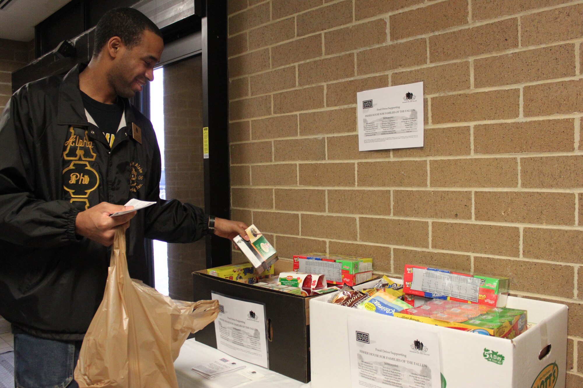 Air Force 1st Lt. Clarence Garden adds a box of coffee to a collection box during the Fisher House for Families of the Fallen food drive at the commissary here Jan. 29, 2011. Lieutenant Garden is assigned to Air Force Mortuary Affairs Operations. (U.S. Air Force photo/Christin Michaud)