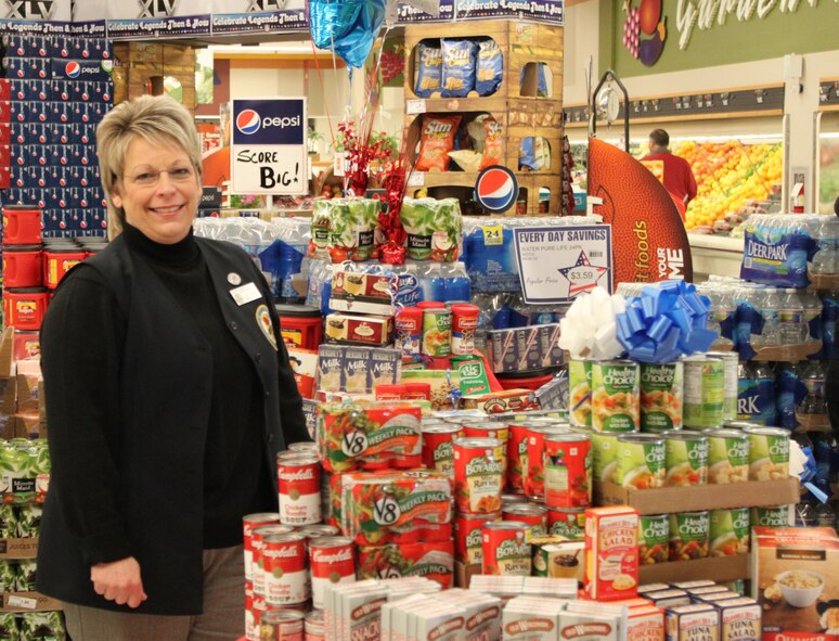 Lisa L. Serrano, Store Director at Defense Commissary Agency at Dover Air Force Base, Del., poses in front of the display her team put together in preparation for a food drive for the Fisher House for Families of the Fallen. Display items were nonperishable items being requested by Friends of the Fallen which are provided to family members who travel to Dover to witness the dignified transfer of their fallen loved ones. (U.S. Air Force photo/Christin Michaud)