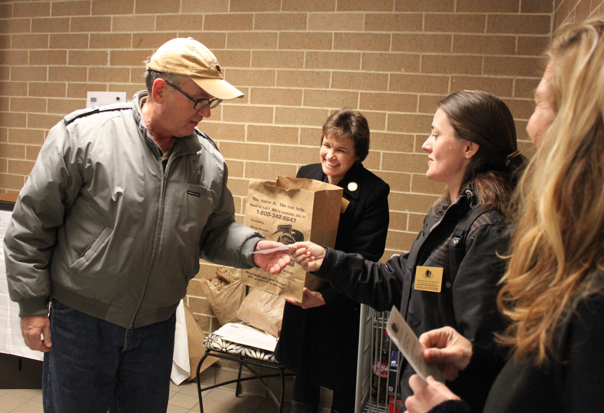 Stephanie Coombs hands a commissary patron a thank you slip after he handed a food donation to Caroline Joyce during the Fisher House for Families of the Fallen food drive Jan. 29, 2011 at the Defense Commissary Agency at Dover Air Force Base, Del. Patrons donated more than $4,500 worth of food during the two-day food drive. (U.S. Air Force photo/Christin Michaud)
