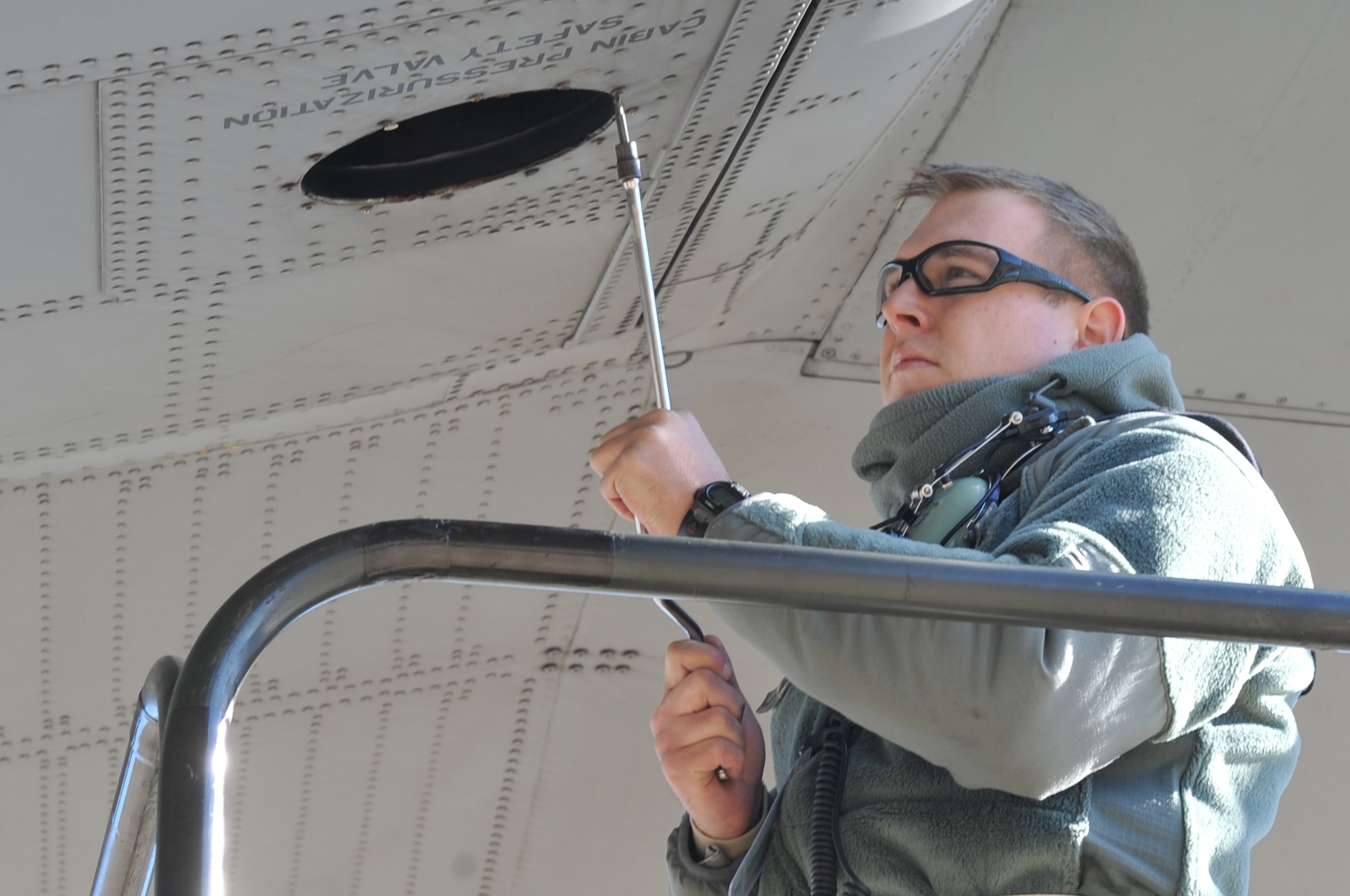 Senior Airman Justin Williams, a 314th Aircraft Maintenance Squadron electrical and environmental specialist, removes a safety valve from a C-130 Jan. 26, 2011, on the flight line at Little Rock Air Force Base Ark. Removal of the safety valve prevents the aircraft from over pressurizing during outflow valve failure. (U.S. Air Force photo by Airman 1st Class Rusty Frank)