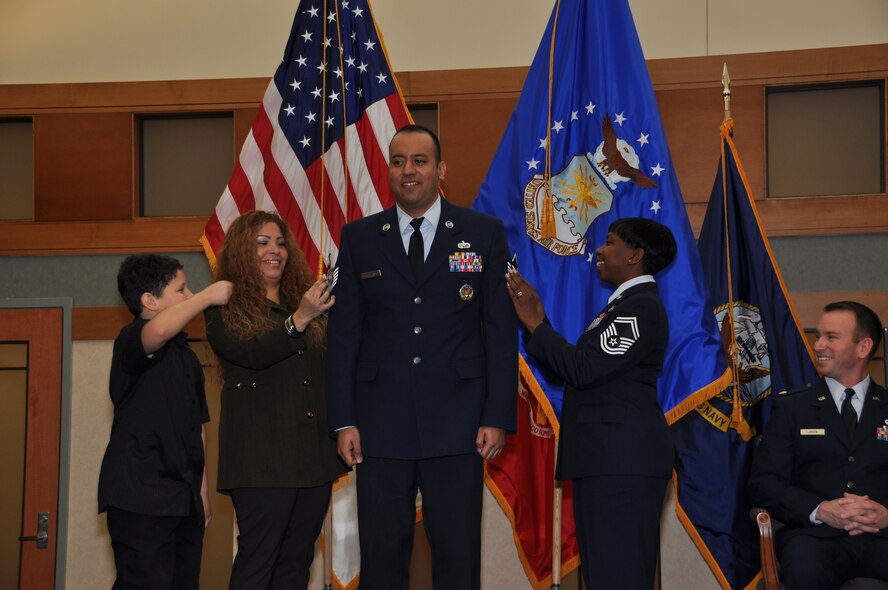 Corey Del Castillo (left) gets ready to help his father Tech. Sgt. Edwin Del Castillo tack on his master sergeant stripes during his promotion ceremony Jan. 31, 2011. Sergeant Del Castillo's wife Lidia and supervisor, Senior Master Sgt. Michelle Williams, also assisted in pinning on the new stripe which moves him to the senior noncommissioned officer tier. Maj. Cory Larsen (right) officiated. (U.S. Air Force photo/Christin Michaud)