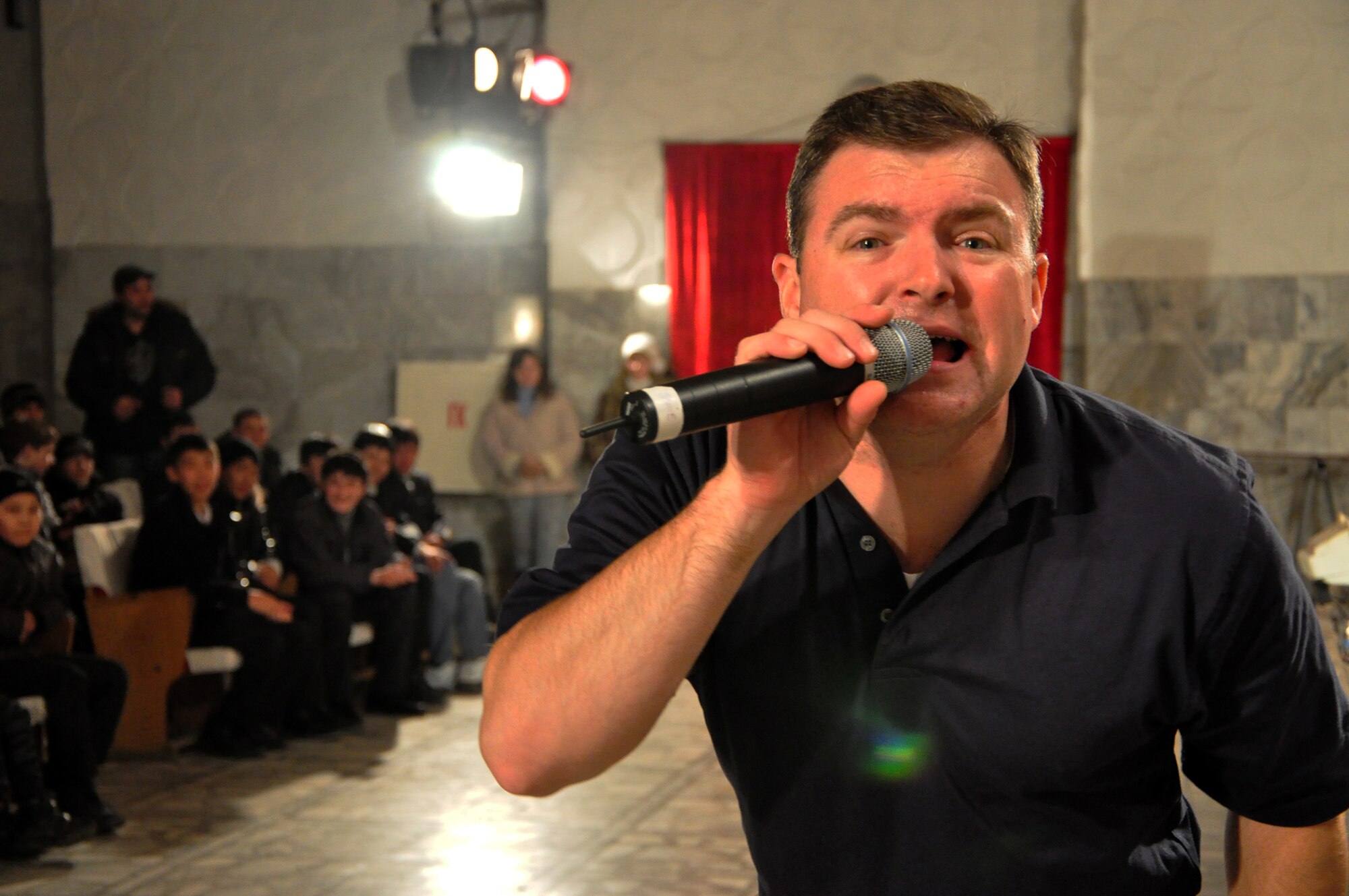Tech. Sgt. Jamie Gilley sings to the camera during a U.S. Air Forces Central band "Starlifter" concert at the "Alyi Parus" House of Culture, Kant, Kyrgyzstan, Jan. 31. Starlifter, based out of Scott Air Force Base, Ill., is currently deployed as the U.S. Air Forces Central Expeditionary Band. These dynamic musicians travel throughout the CENTAF Area of Responsibility promoting troop morale, diplomacy and outreach to host nation communities. (U.S. Air Force photo/ Master Sgt. Daniel H. Nathaniel III) 