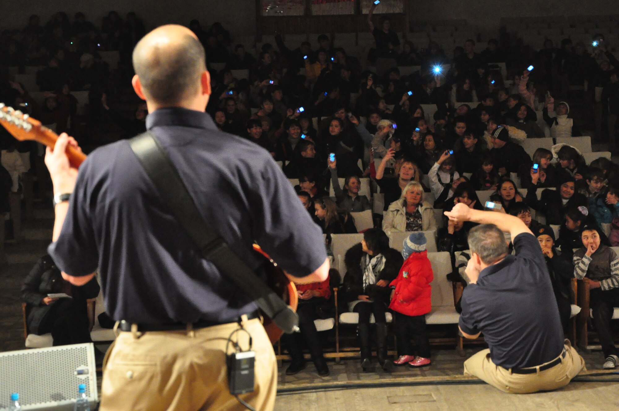 Students light up their cellphones and sway to the vocals of Tech. Sgt. Jamie Gilley during a U.S. Air Forces Central band "Starlifter" concert at the "Alyi Parus" House of Culture, Kant, Kyrgyzstan, Jan. 31. Starlifter, based out of Scott Air Force Base, Ill., is currently deployed as the U.S. Air Forces Central Expeditionary Band. These dynamic musicians travel throughout the CENTAF Area of Responsibility promoting troop morale, diplomacy and outreach to host nation communities. (U.S. Air Force photo/ Master Sgt. Daniel H. Nathaniel III) 
