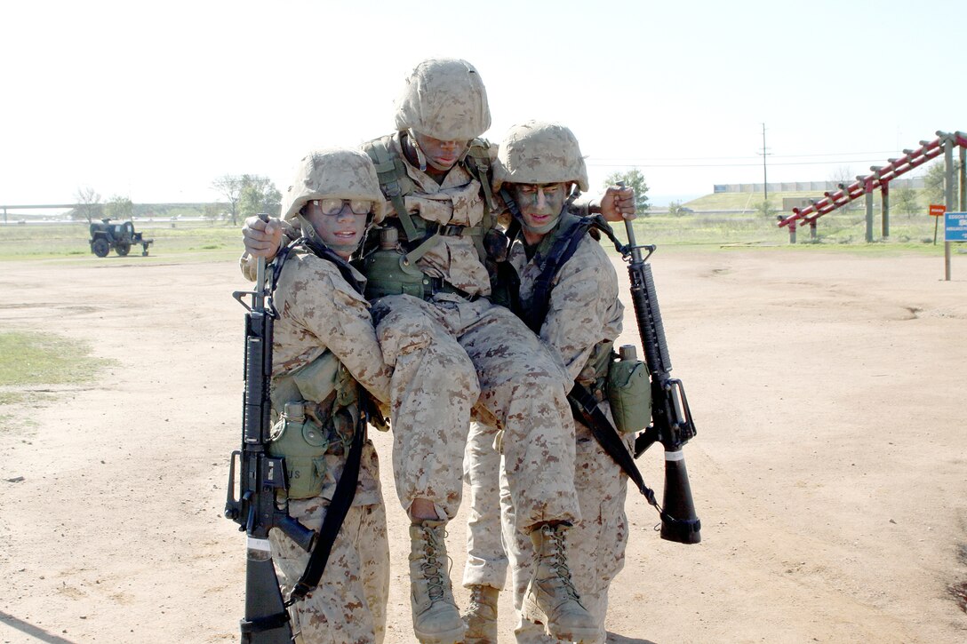 Recruits Gabriel A. Becerra, left, and Luke A. Burrow, right, perform a chair carry to move simulated casualty, Recruit Craig E. Candies Jr., to their platoon’s designated checkpoint before he can return to the Crucible. The recruits are members of Platoon 3209, Company I