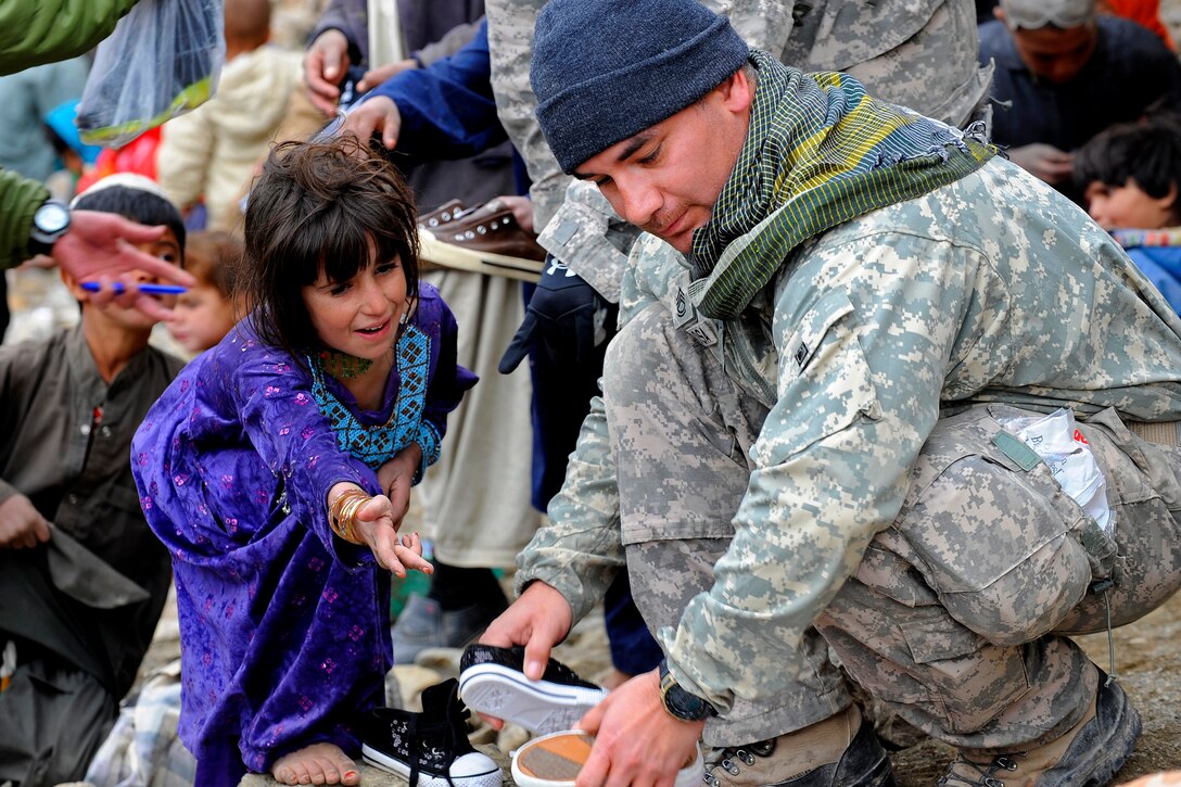 U.S. Army Sgt. 1st Class Manuel Delarosa gives a pair of shoes to a young Afghan girl. Delarosa and Afghan security forces distribute winter supplies in Safidar village, Afghanistan, Feb. 1, 2011. Delarosa is assigned to the Provincial Reconstruction Team Zabul.