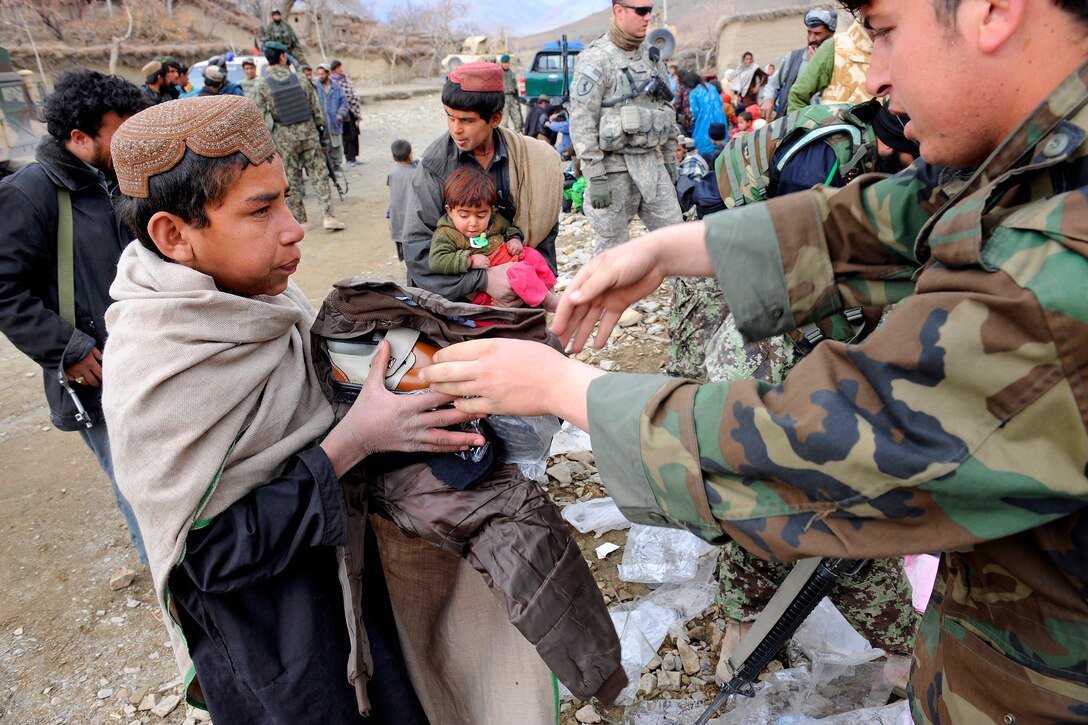 An Afghan youth receives winter supplies of shoes and clothes from Afghan security forces and members of the Provincial Reconstruction Team Zabul, in the Safidar village, Afghanistan, Feb. 1, 2011.