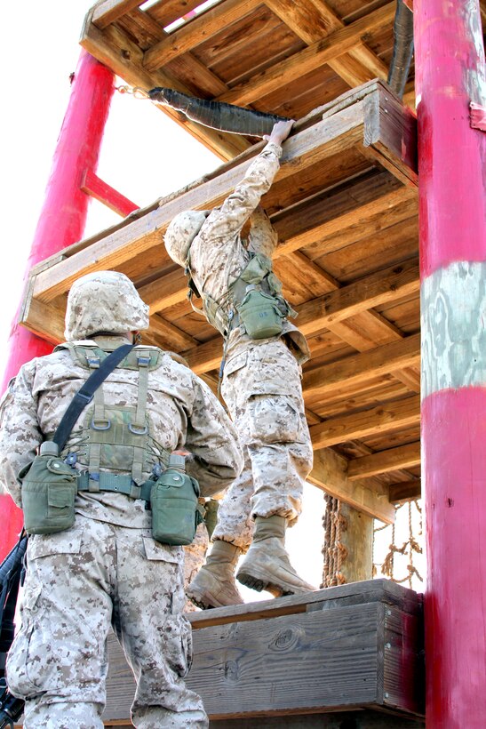 Recruits from Platoon 3209, Company I, help each other to reach the second story of the Dunham’s Ascent obstacle. The recruits must climb to the fourth story to reach and save a simulated casualty.