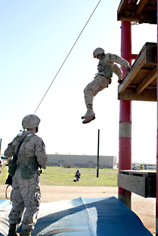 ::r::::n::Recruit Gabriel Becerra, Platoon 3209, Company I, leaps from the second story of the Dunham’s Ascent obstacle during the Crucible. If the recruits do not maintain a low-profile they may become simulated casualties and must begin the exercise again. ::r::::n::