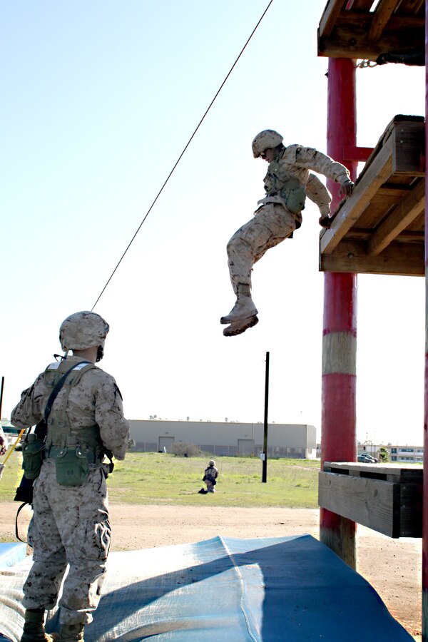 ::r::::n::Recruit Gabriel Becerra, Platoon 3209, Company I, leaps from the second story of the Dunham’s Ascent obstacle during the Crucible. If the recruits do not maintain a low-profile they may become simulated casualties and must begin the exercise again. ::r::::n::