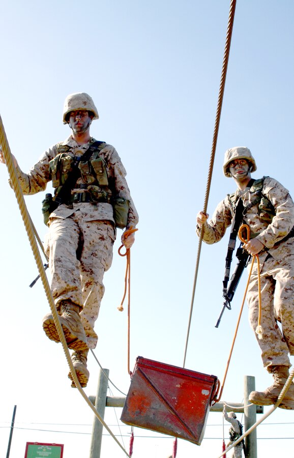 Recruit Case Fenster, left, and Recruit Dillon Erickson, Platoon 3209, Company I, use rope to carry an ammunition can across a rope bridge during the Crucible. Holder’s Stance is an event used to simulate a resupply mission under extreme conditions.