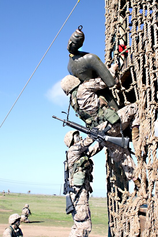 Recruits Jacob R. Brown, top, and Enrique G. Calderon, Platoon 3209, Company I, work together to bring a simulated casualty down the rope net to get medical attention during the Crucible.