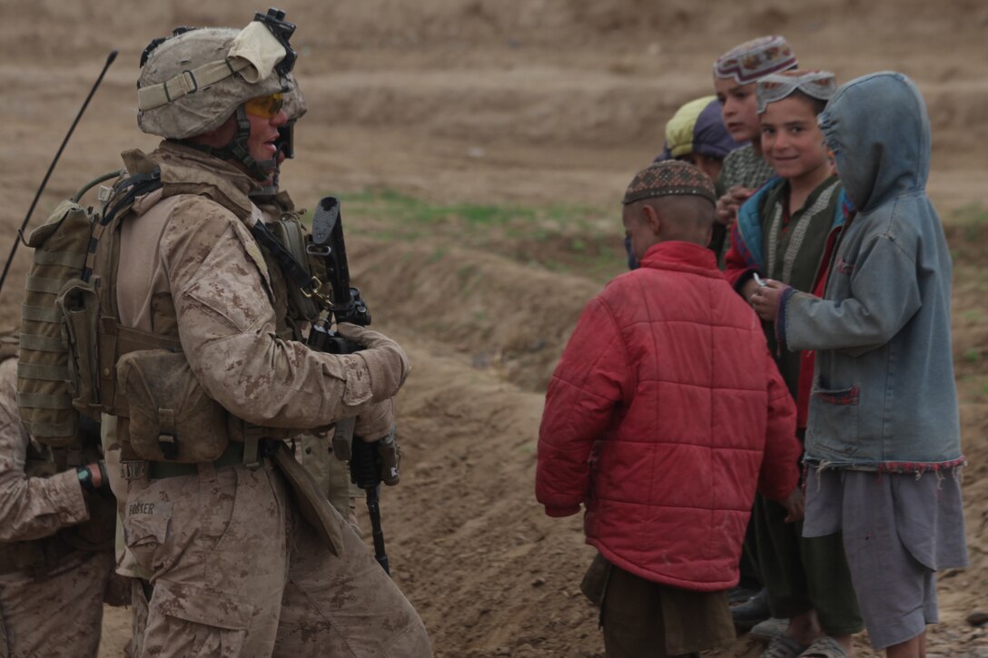 U.S. Marine Corps Gunnery Sgt. John M. Foster III, platoon sergeant for 1st Platoon, Company L, Battalion Landing Team 3/8, 26th Marine Expeditionary Unit, Regimental Combat Team 2, converses with local Afgan children while on patrol near Combat Outpost Ouellette in the Helmand province, Afghanistan, Feb. 2, 2011. Elements of the 26th Marine Expeditionary Unit deployed to Afghanistan to provide regional security in Helmand province in support of the International Security Assistance Force.