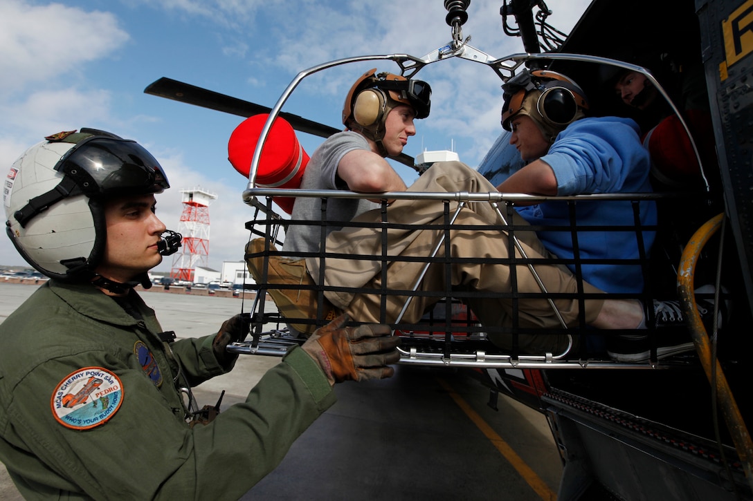 Cpl. Bruce D. Barner, left, a search and rescue crew chief with Marine Transport Squadron 1, demonstrates the hoisting capabilities of the HH-46E search and rescue helicopter to two Craven County high school students at Cherry Point Feb. 2. Richard Bradford, right, a senior at Havelock High School, and Mathew Price, a junior at New Bern High School, visited the air station with several other Craven County students, as part of National Groundhog Job Shadow Day.::r::::n::::r::::n::