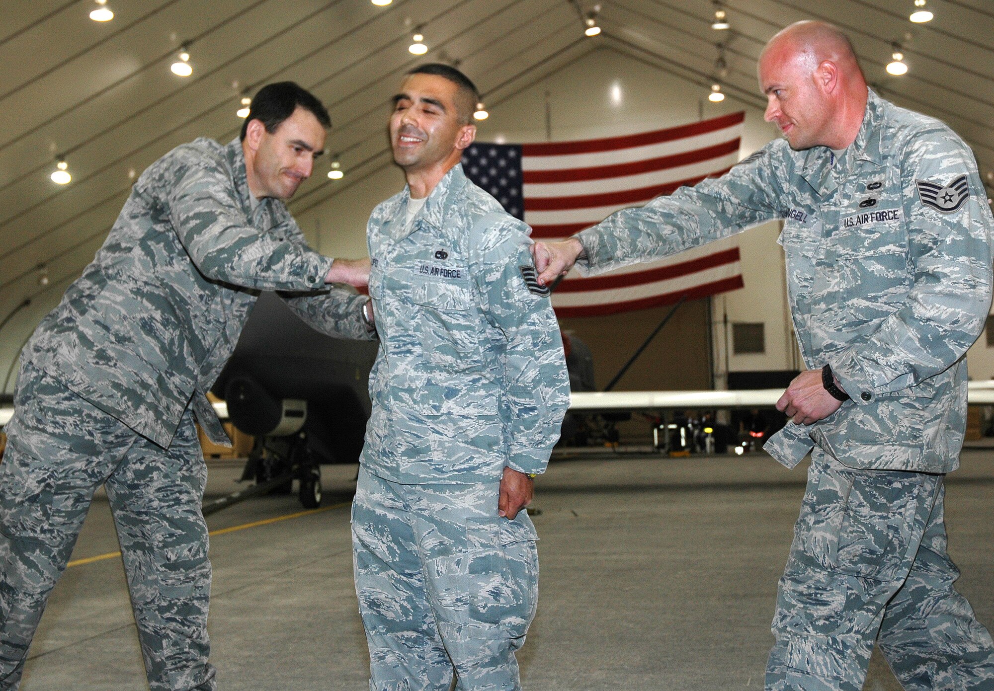 Brig. Gen. Mike Minahan, 380th Air Expeditionary Wing commander, tacks promotion stripes on a surprised Staff Sgt. Daniel Lopez with the assistance of Staff Sgt. Brian Angell, 380th Expeditionary Maintenance Squadron, during a recent 380th EAMXS formation. Tech. Sgt. Lopez was awarded the promotion through the Air Force's Stripes for Exceptional Performers (STEP) program. (U.S. Air Force photo by Master Sgt. Julie Briden-Garcia)