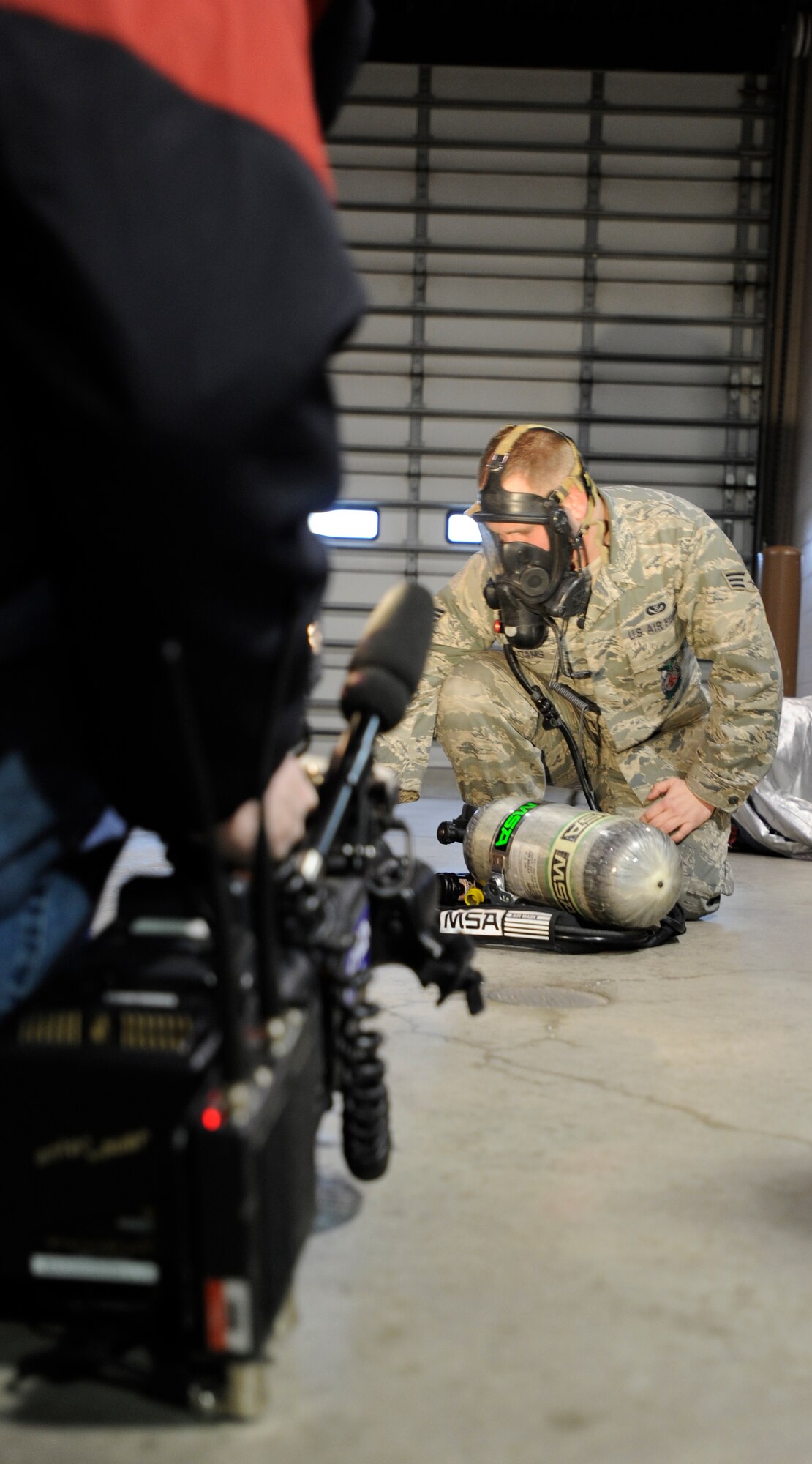 Senior Airman Jared Adams, 22nd Civil Engineer Squadron firefighter, demonstrates the self contained breathing apparatus to Wichita’s KWCH-TV Jan. 31, 2011, McConnell Air Force Base, Kan. Airman Adams was recognized by KWCH-TV for saving an elderly couple from a house fire.  (U.S. Air Force photo/Airman 1st Class Armando A. Schwier-Morales)
