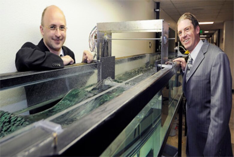 Marcus Roemer (left) and Dr. Stefan Siegel stand near a water tank containing a 1:300 scale model of a wave energy converter they designed in the fall of 2008. Officials from the Department of Energy and the National Science Foundation have invested in a series of larger tests with a 1:10 scale model of the Academy's wave energy converter, which has harnessed upwards of 99 percent of energy in a wave in tests here. (U.S. Air Force photo/Rachel Boettcher)
