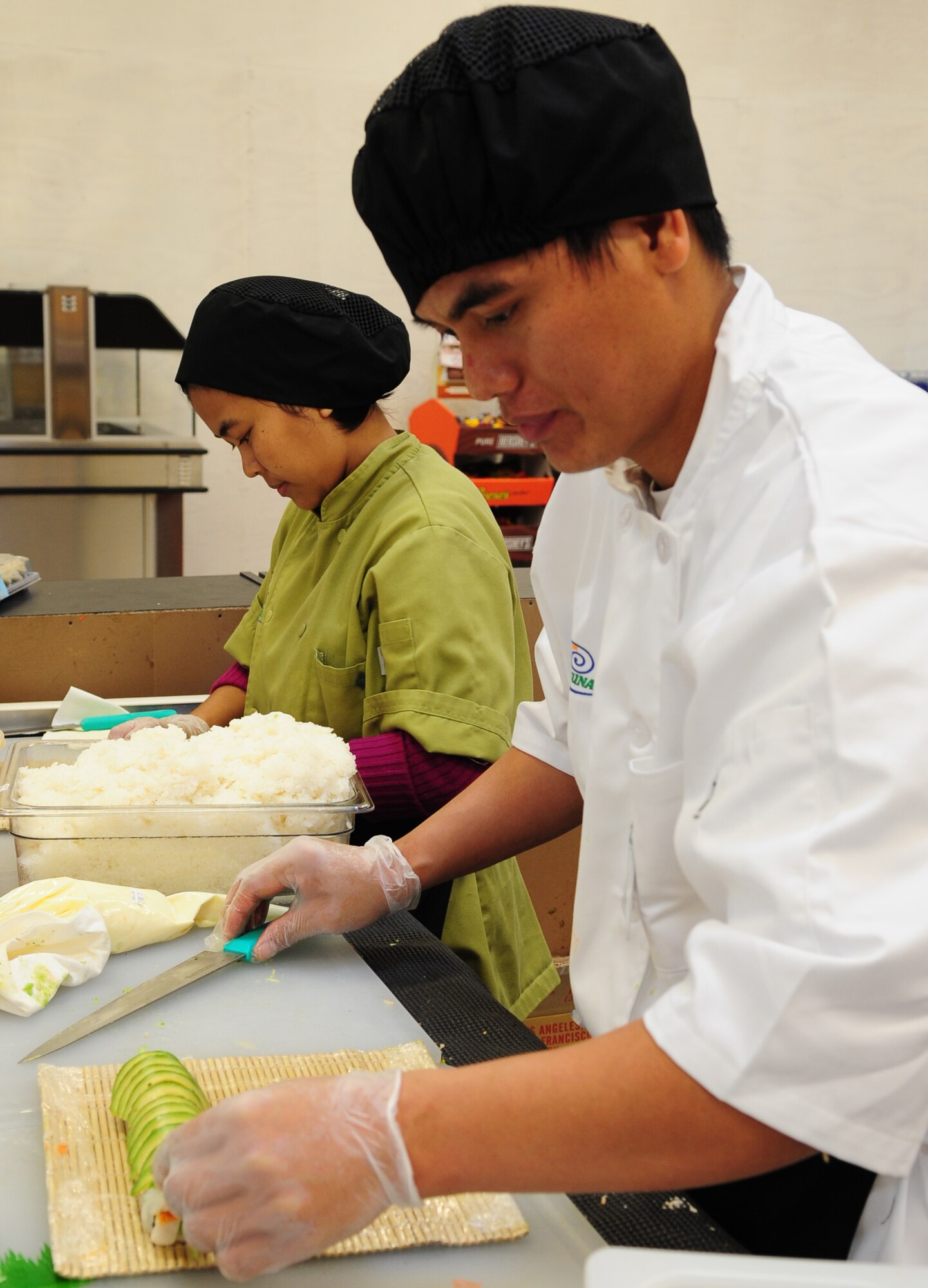 MOODY AIR FORCE BASE, Ga.-- Sut Mug, sushi bar worker,  prepares a California roll as Niang Lian, sushi bar worker, rolls rice around sushi at the new addition to the Moody Commissary Feb. 2. The commissary now provides fresh sushi daily as a healthy meal for shoppers. (U.S. Air Force photo/Senior Airman Stephanie Mancha)(RELEASED)