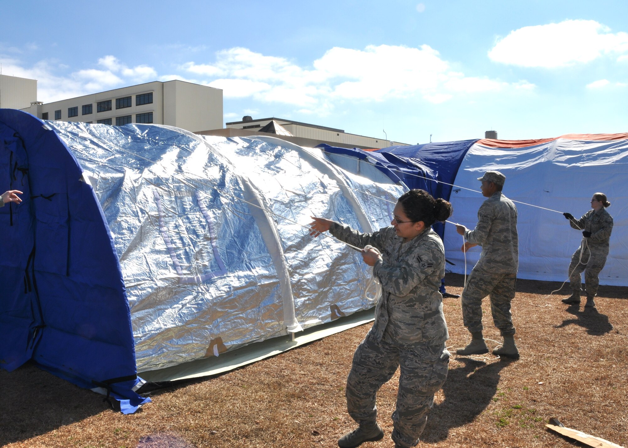 Airman 1st Class Karla Martinez and Airman Yan Cruz, 81st Medical Support squadron, and Airman 1st Classs Erica Gilbertson, 81st Medical Operations Squadron, pull the exterior canvas layer over the smallest of the three tents as they train to erect the “Blu-Med” system Jan. 19.  (U.S. Air Force photo by Steve Pivnick)