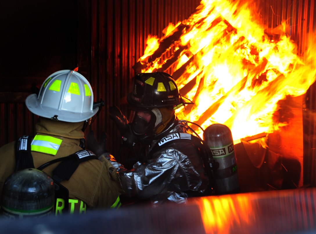 (Left) Col. Trent Edwards, 28th Mission Support Group commander, trains as a firefighter during a controlled indoor fire with Mr. Bill Cina, 28th Civil Engineer Squadron fire truck operator, at Ellsworth Air Force Base, S.D., Jan. 27.  The fire is set inside a training building used solely by the fire department. (U.S. Air Force photo/Senior Airman Anthony Sanchelli)
