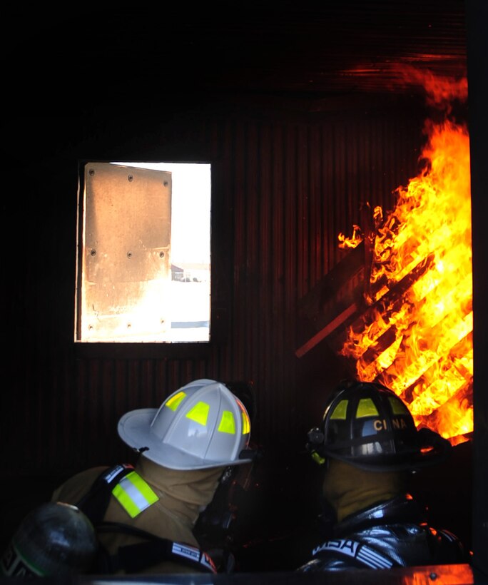 (Left to right) Col. Trent Edwards, 28th Mission Support Group commander, trains as a firefighter during a controlled indoor fire with Mr. Bill Cina, 28th Civil Engineer Squadron fire truck operator, at Ellsworth Air Force Base, S.D., Jan. 27.  The fire is set inside a training building used solely by the fire department. (U.S. Air Force photo/Senior Airman Anthony Sanchelli)
