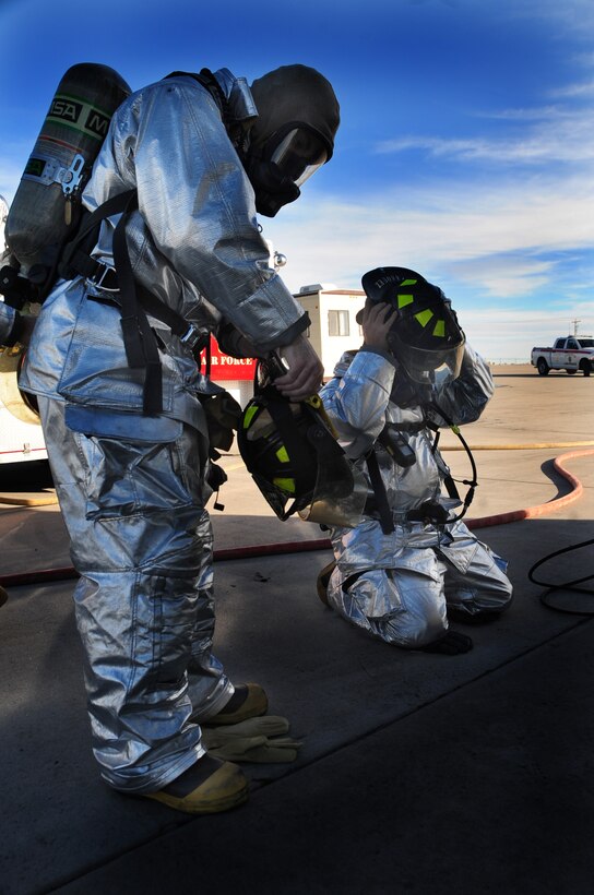 (Right to left) Senior Airman John Vasquez and Airman Robert Marriot, 28th Civil Engineer Squadron firefighters, gear up before fire training at Ellsworth Air Force Base, S.D., Jan. 27.  The fire department trained to put out indoor fires with Col. Trent Edwards, 28th Mission Support Group commander. (U.S. Air Force photo/Senior Airman Anthony Sanchelli)
