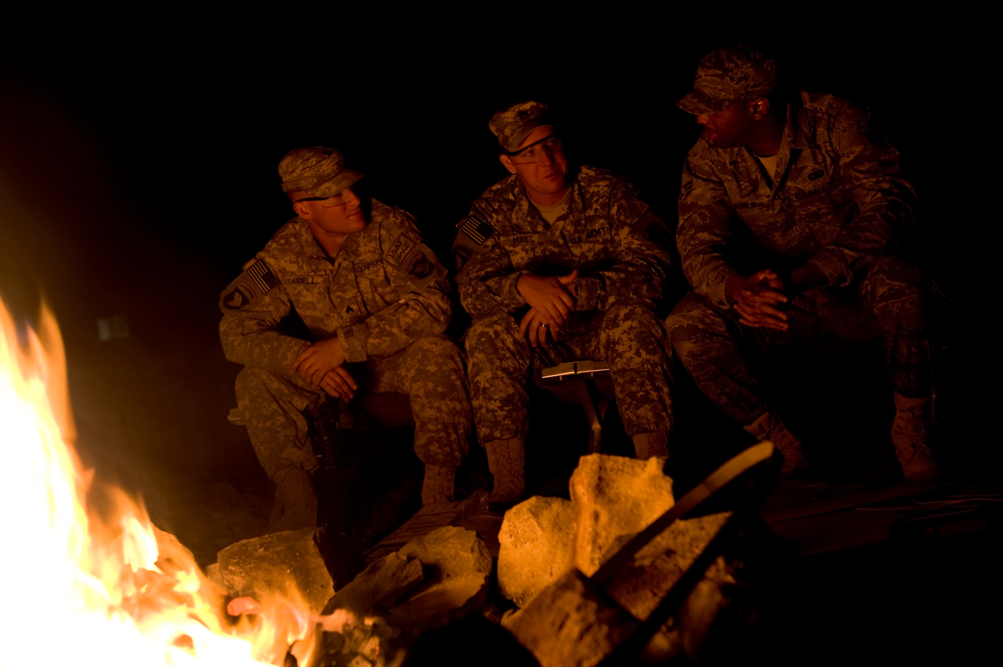 Staff Sgt. Dustin Hall and  Sgt. Robert Odell Task Force Currahee, 4th Brigade, 101st Airborne Division, sit and chat with Senior Airman Mychael White, deployed from the 56th Communications Squadron at Luke AFB, Ariz, while they warm up at a bonfire at Forward Operating Base Waza K'wah, Paktika province, Afghanistan.The bonfire is a weekly ritual where both Army and Air Force members gather together to relax and enjoy each others company and help lift morale. Senior Airman White is one of four Air Force members assigned to the FOB for communications support. (U.S. Air Force photo by Master Sgt. Adrian Cadiz)
