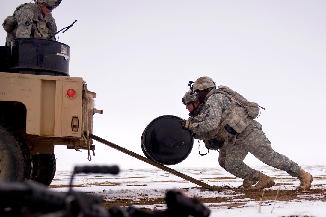 Two U.S Army soldiers roll fuel barrels up a vehicle ramp near Forward Operating Base Waza K'wah in Paktika province, Afghanistan, Jan. 29, 2011. 