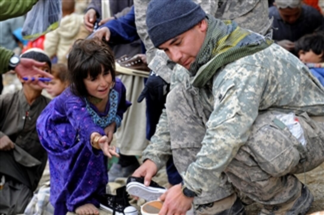 U.S. Army Sgt. 1st Class Manuel Delarosa finds a pair of shoes for a young girl while helping Afghan National Security Forces distribute winter supplies in Safidar village, Afghanistan, on Feb. 1, 2011.  Delarosa is assigned to the Provincial Reconstruction Team Zabul, Shinkai Detachment.  